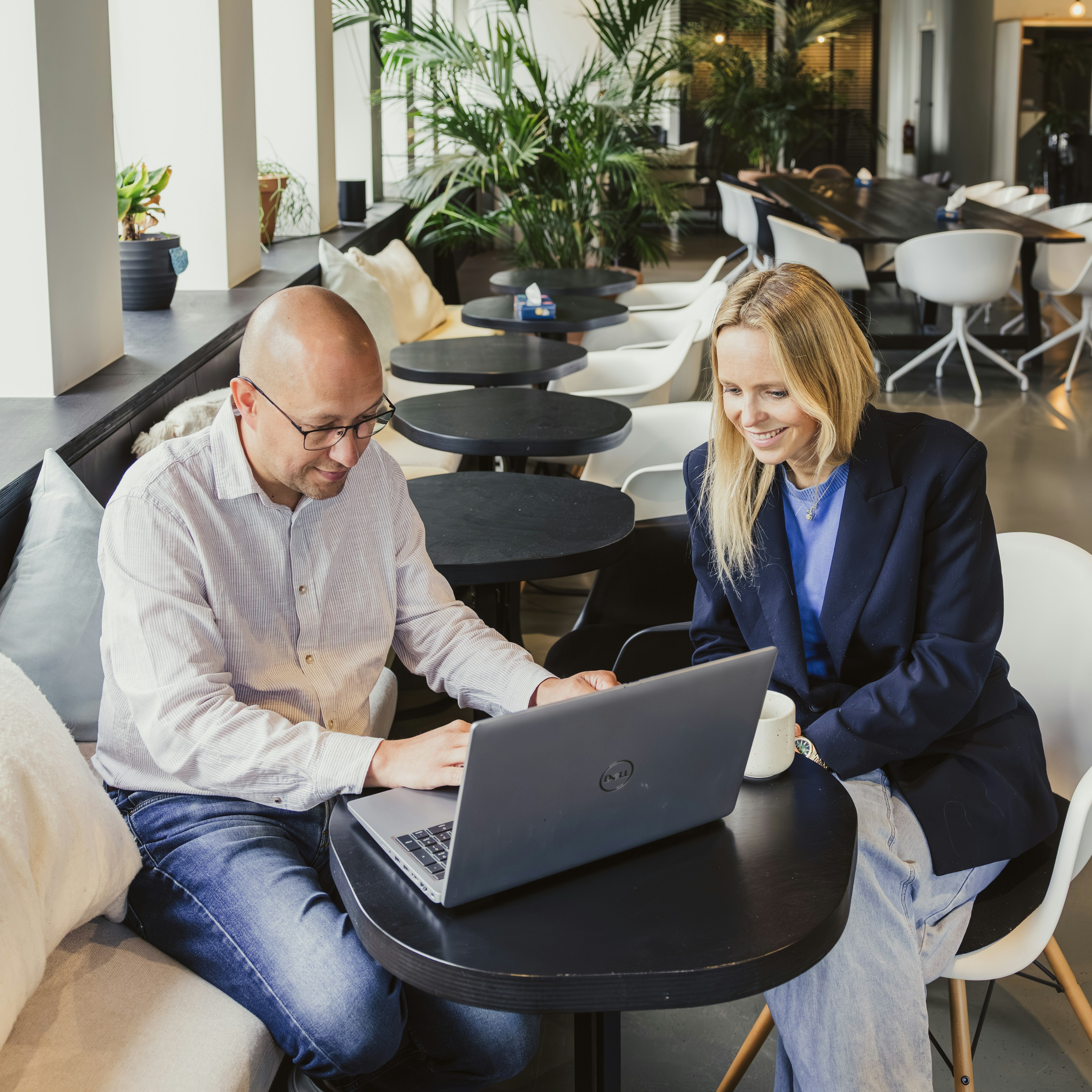 Two colleagues working on a laptop in an office lounge