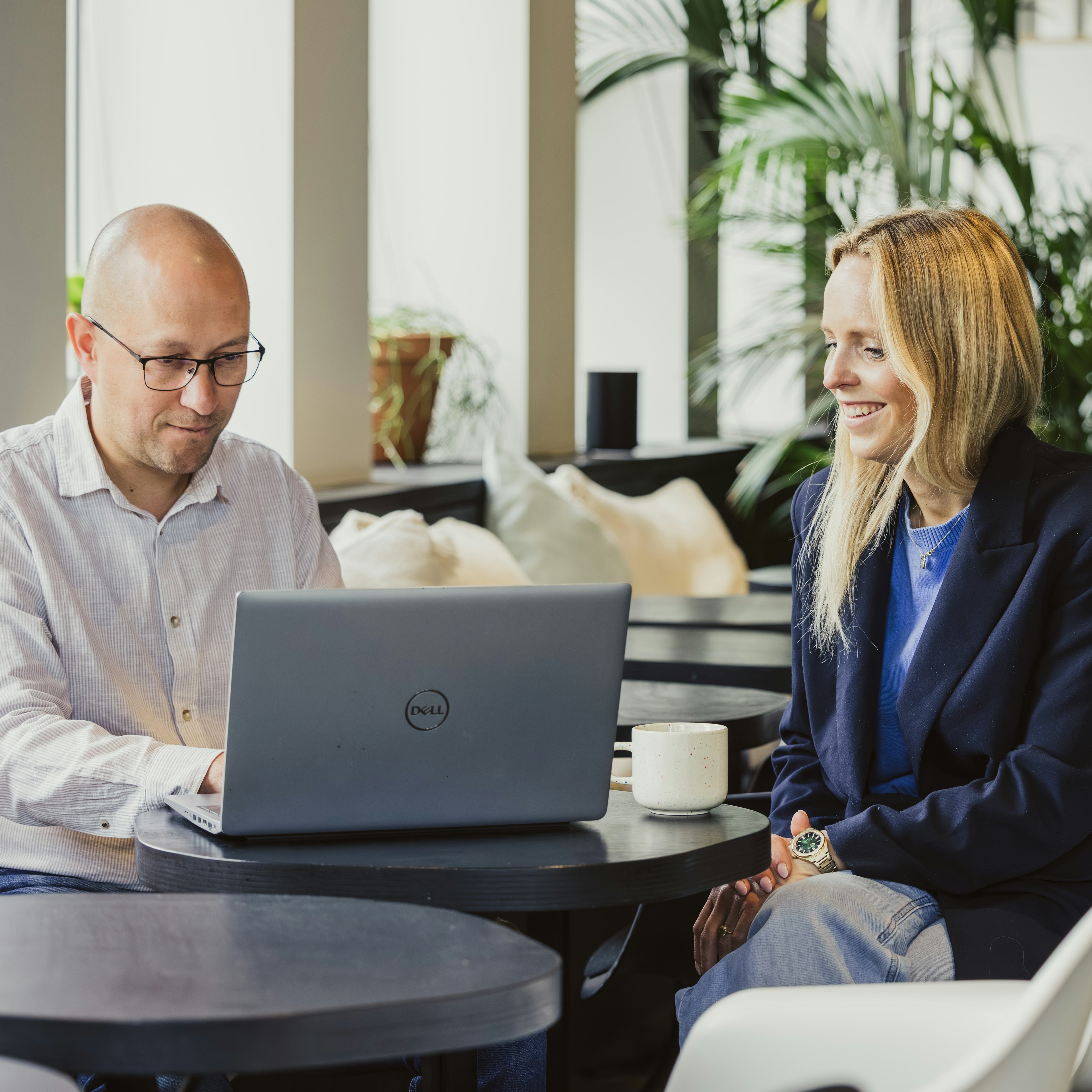 Smiling coworkers consulting a laptop over coffee
