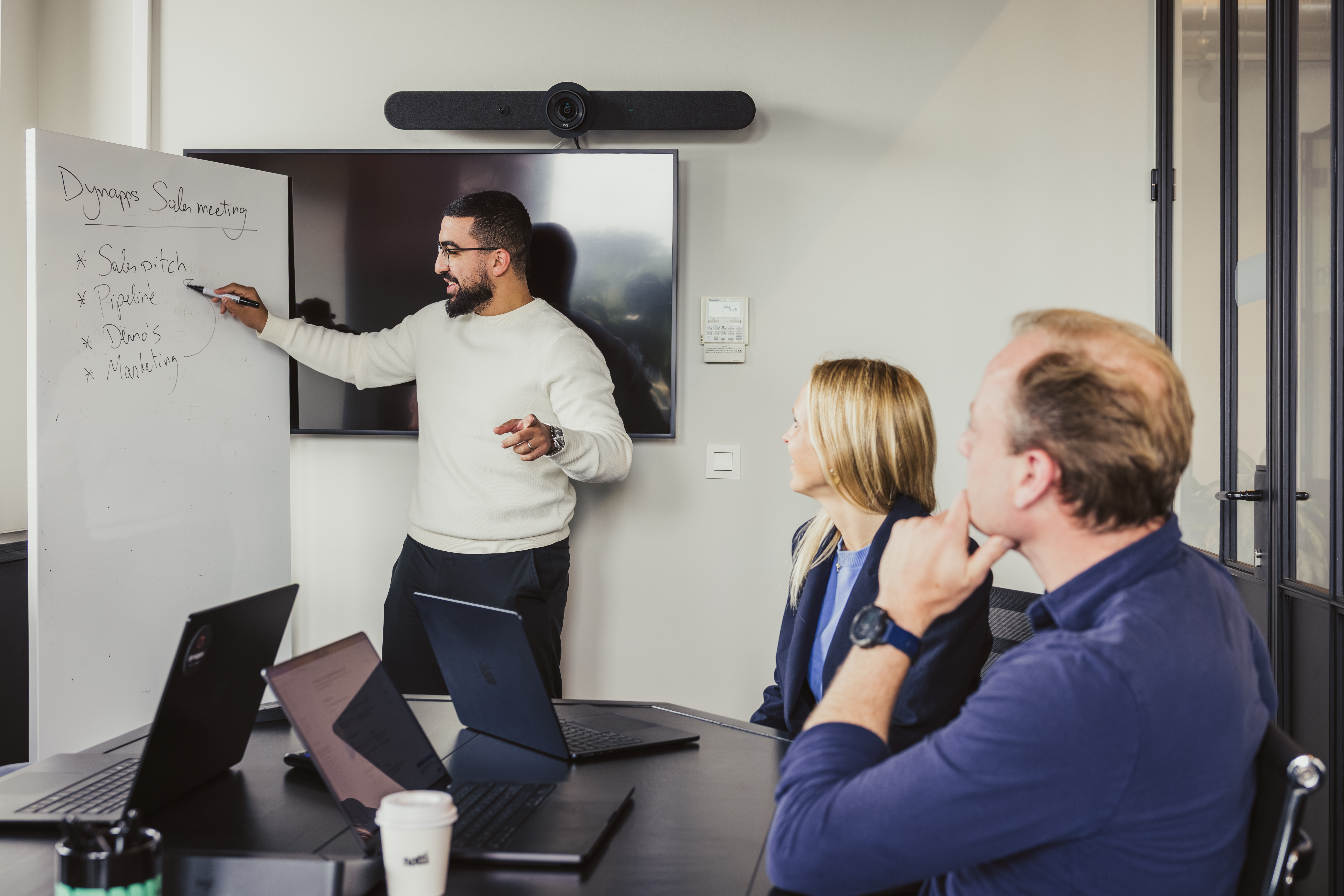 Consultant pointing at whiteboard in a Dynapps sales meeting