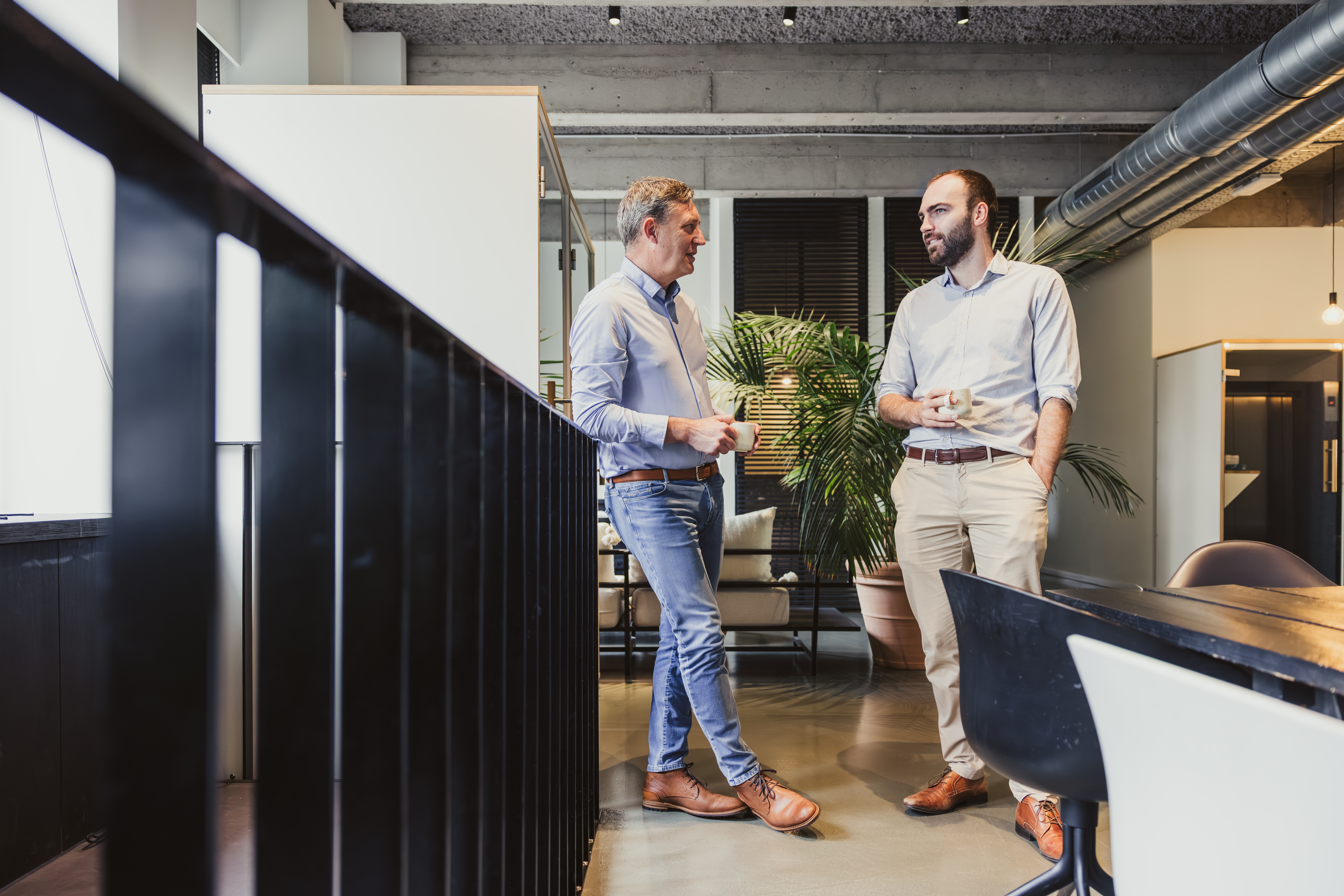 Two colleagues talking with coffee in a modern office