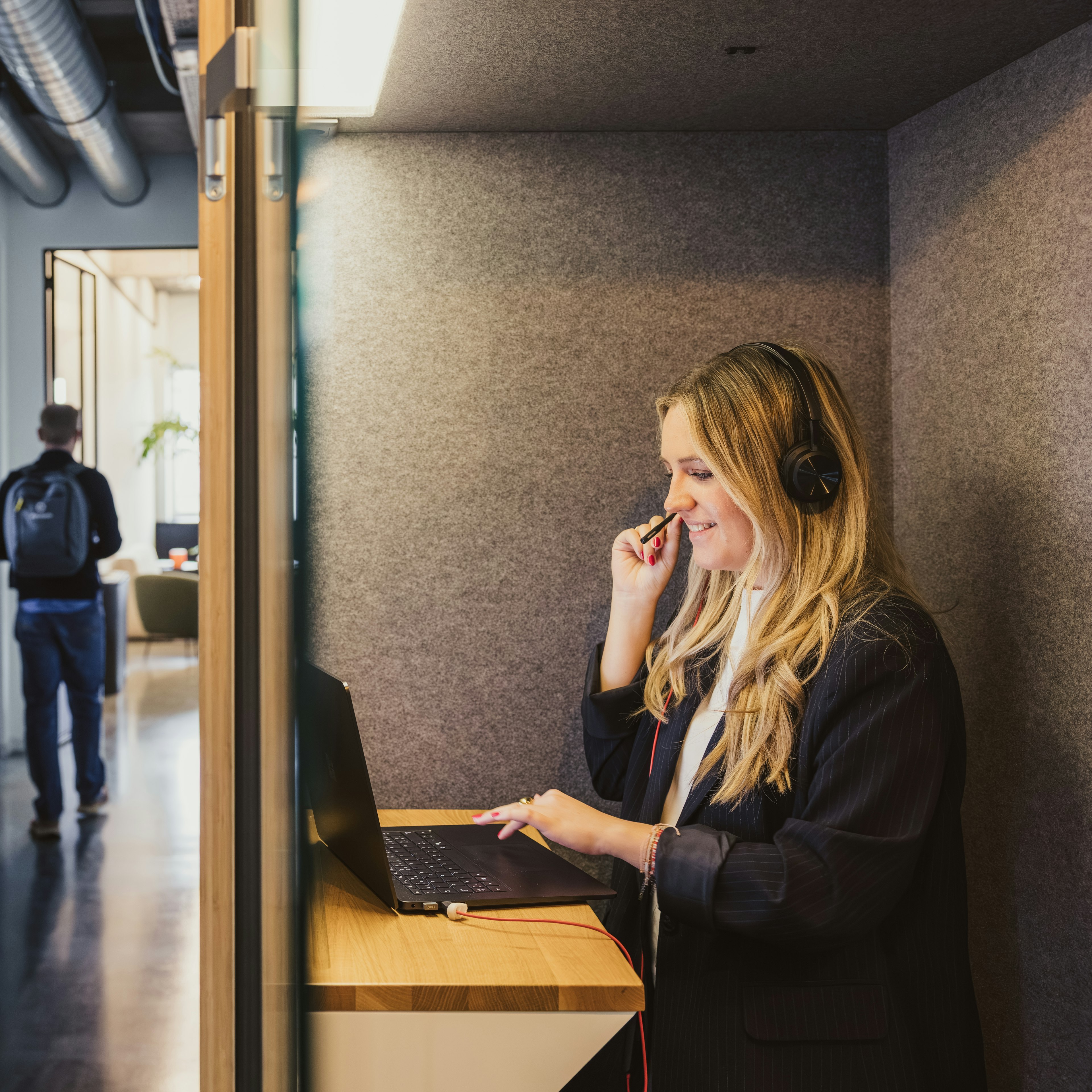 Un consultant en train de passer un appel avec un casque dans une cabine équipée d'un bureau debout