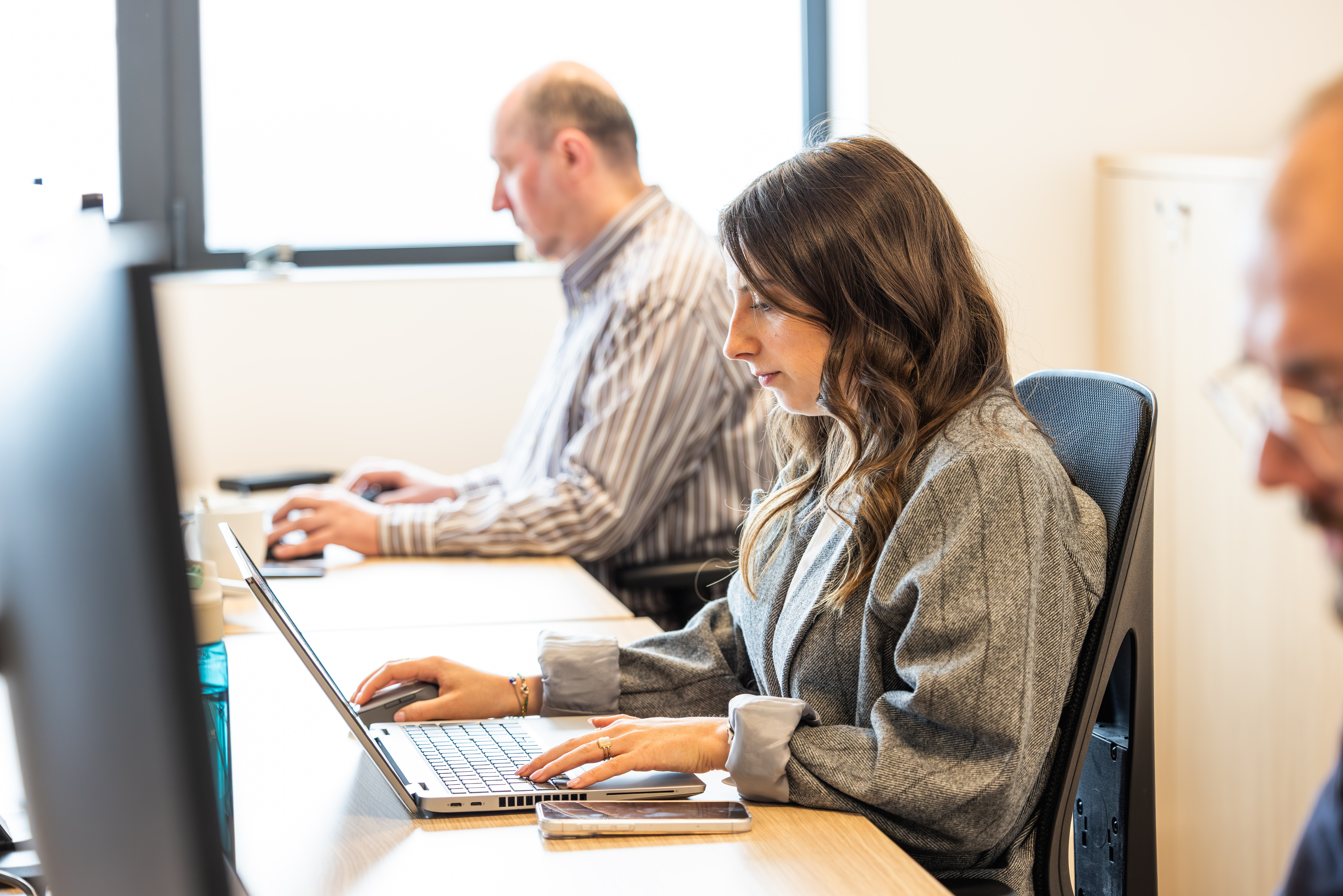 Colleagues working on laptops at a shared office desk