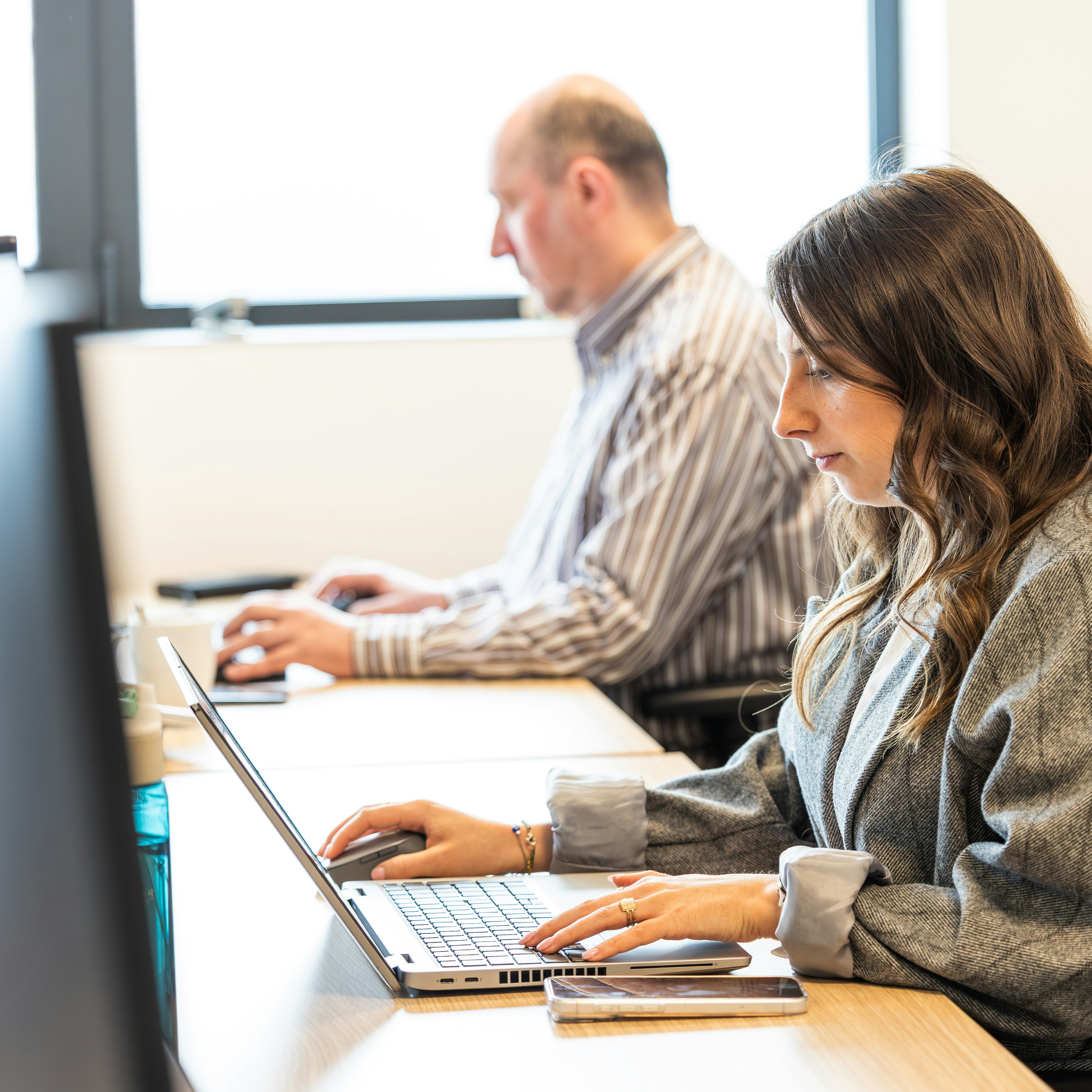 Des collègues travaillant sur leurs ordinateurs portables à un bureau partagé