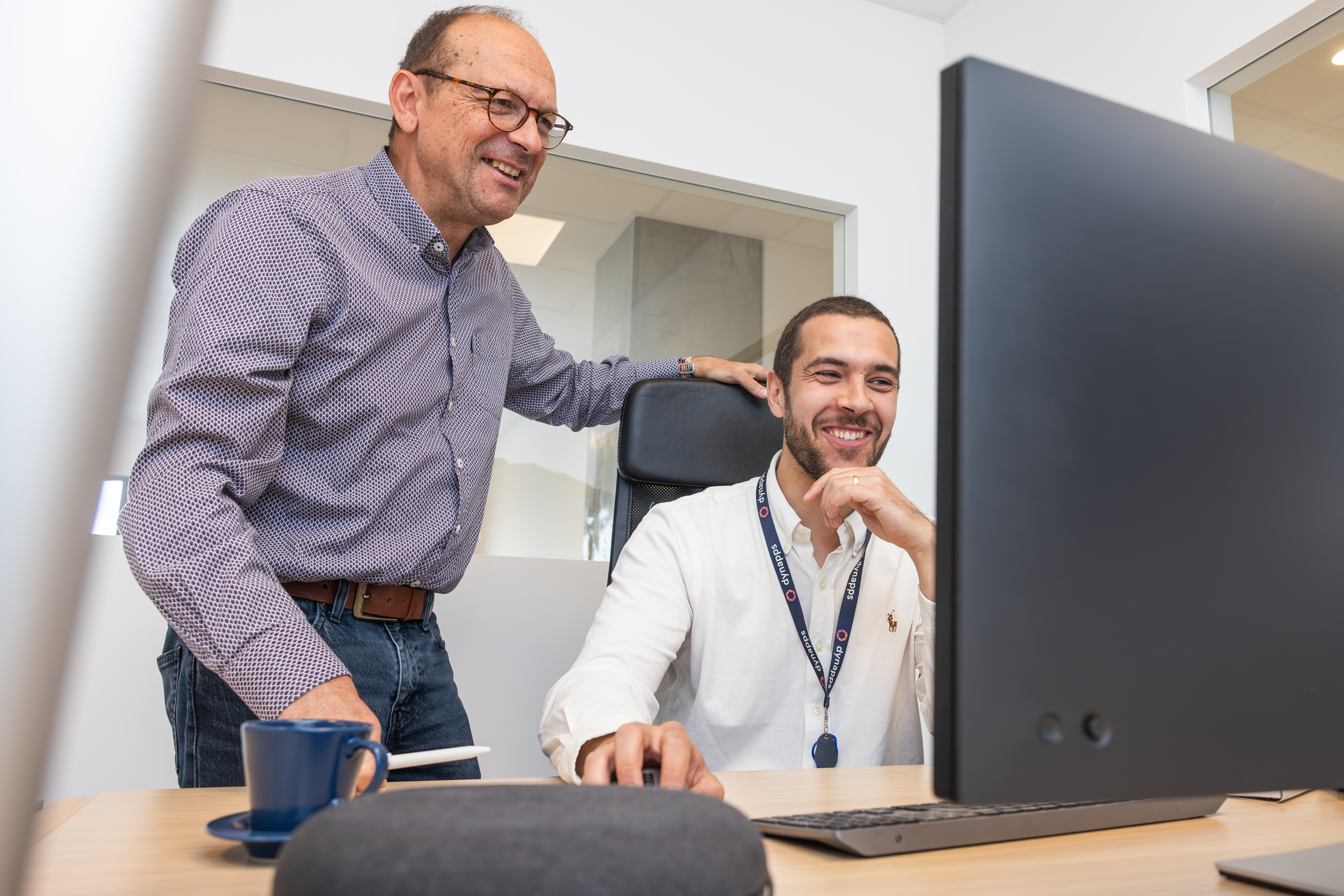 Deux collègues souriants regardant l'écran d'un ordinateur