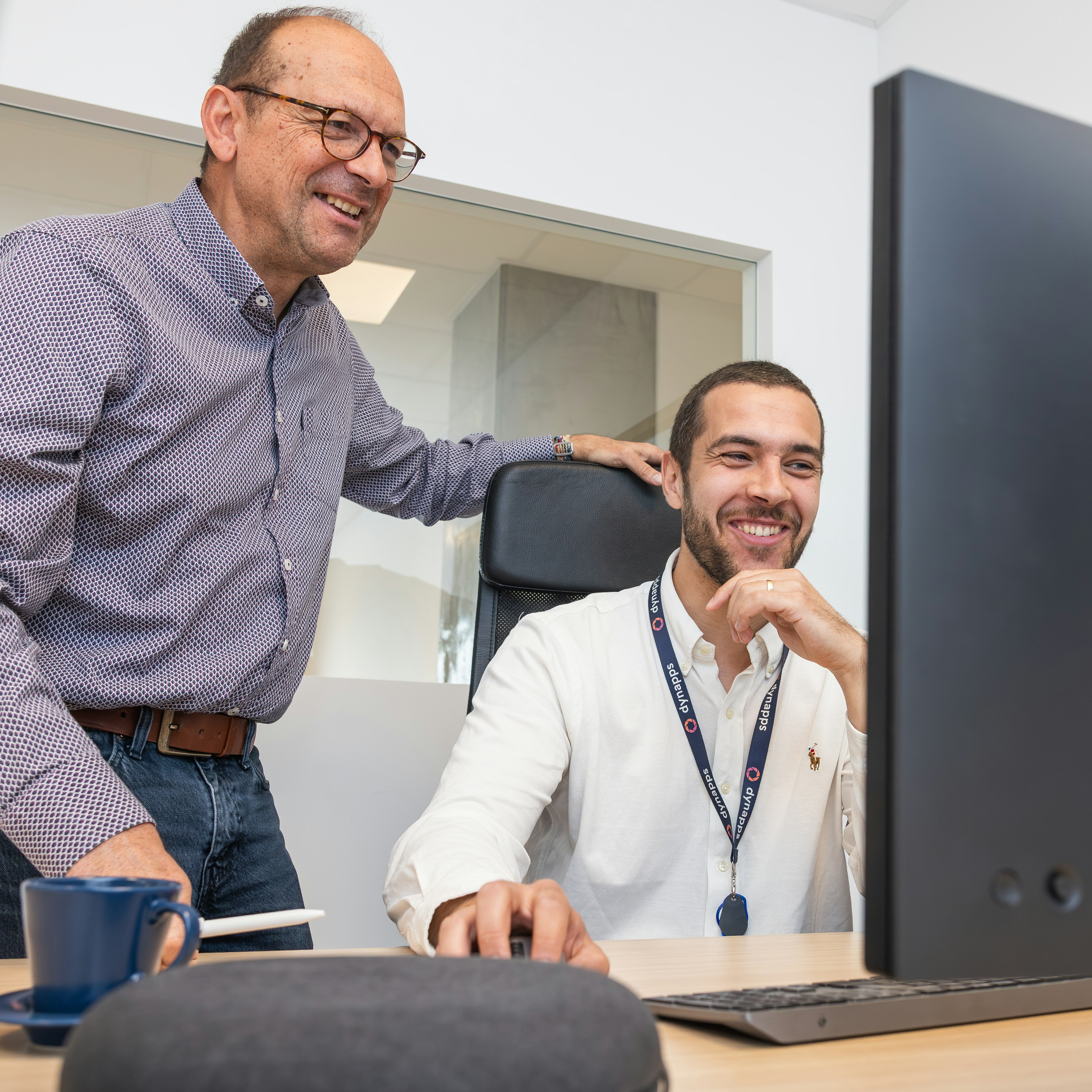 Deux collègues souriants regardant l'écran d'un ordinateur