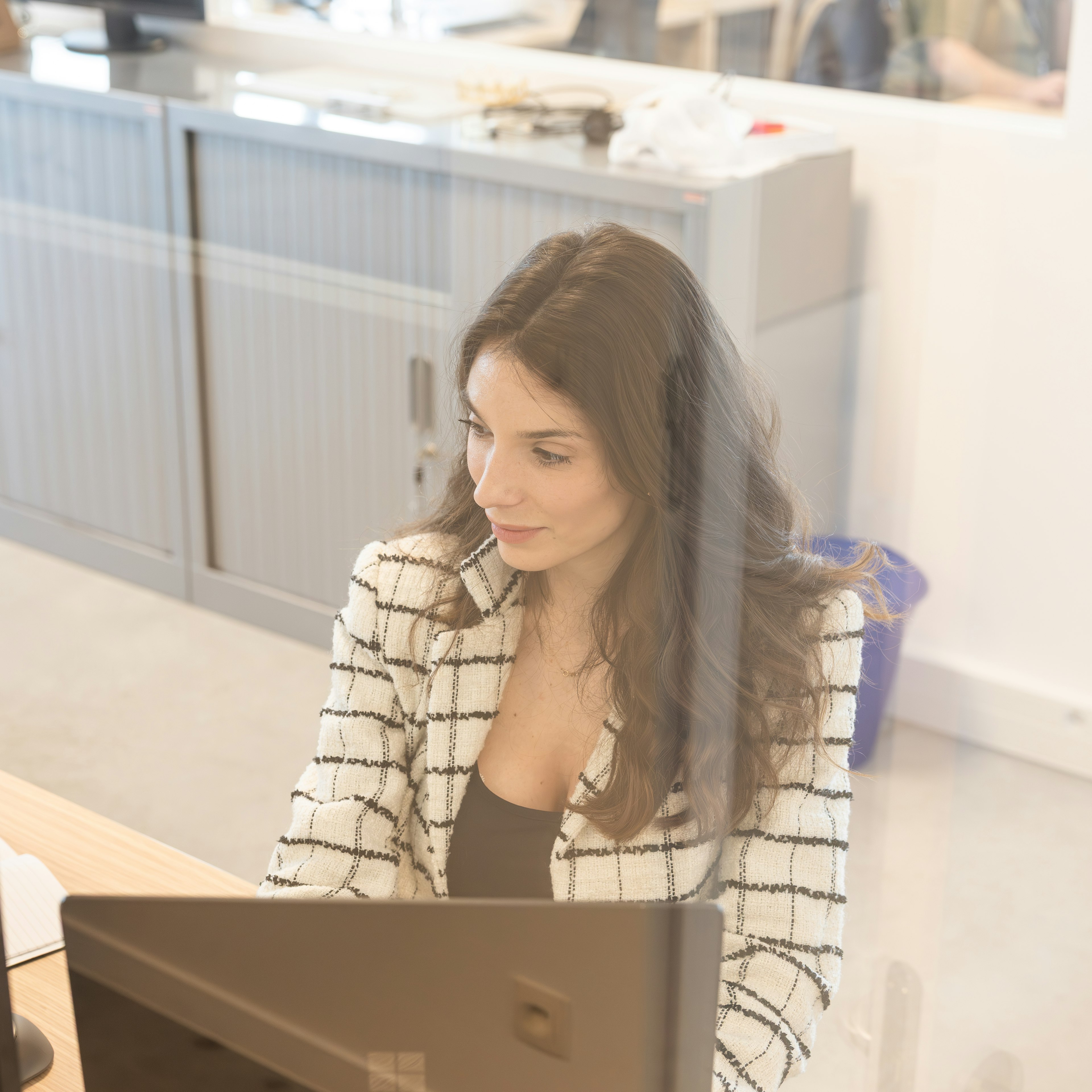 Woman working on a laptop in an open-plan office