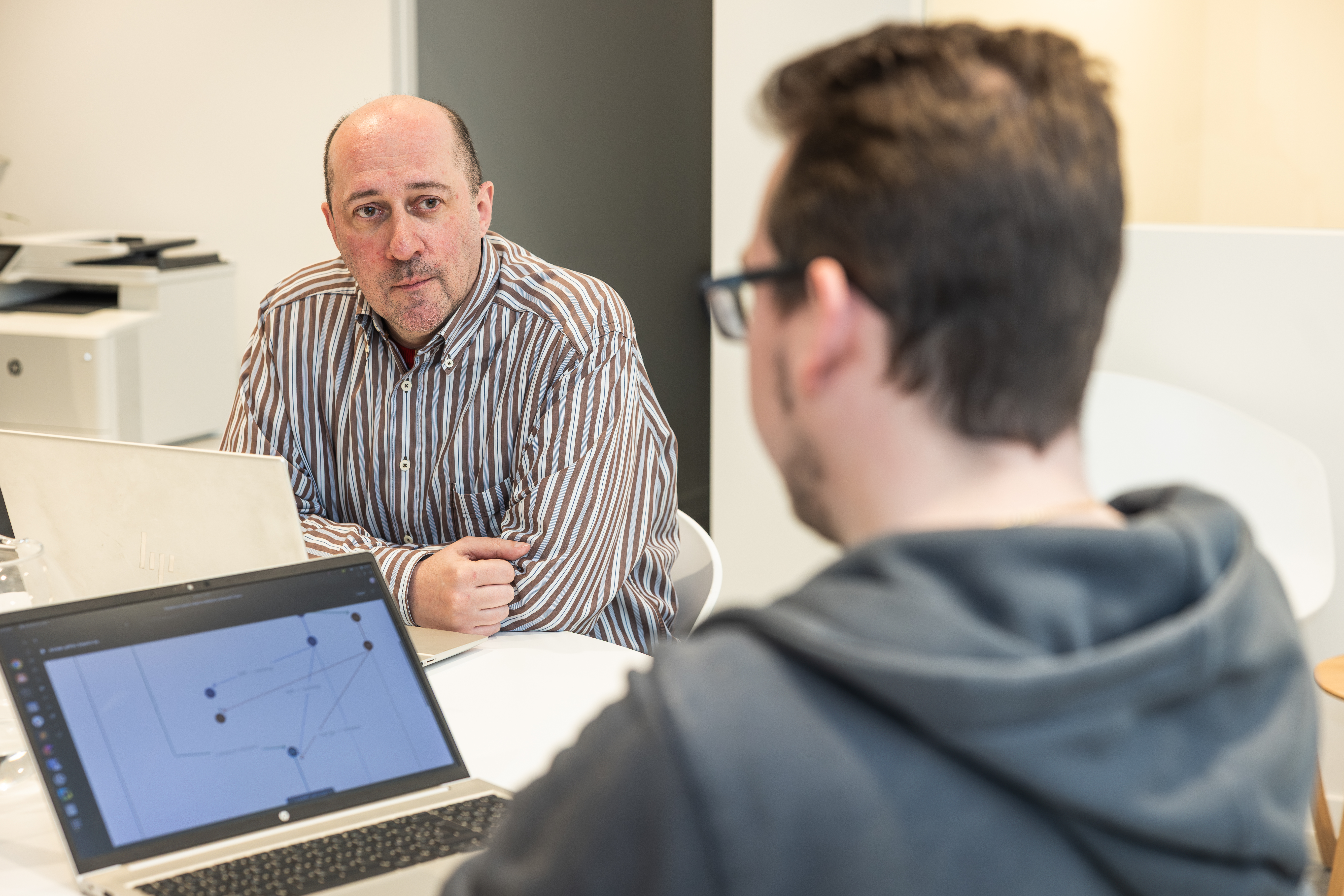 Two colleagues in discussion over a laptop diagram