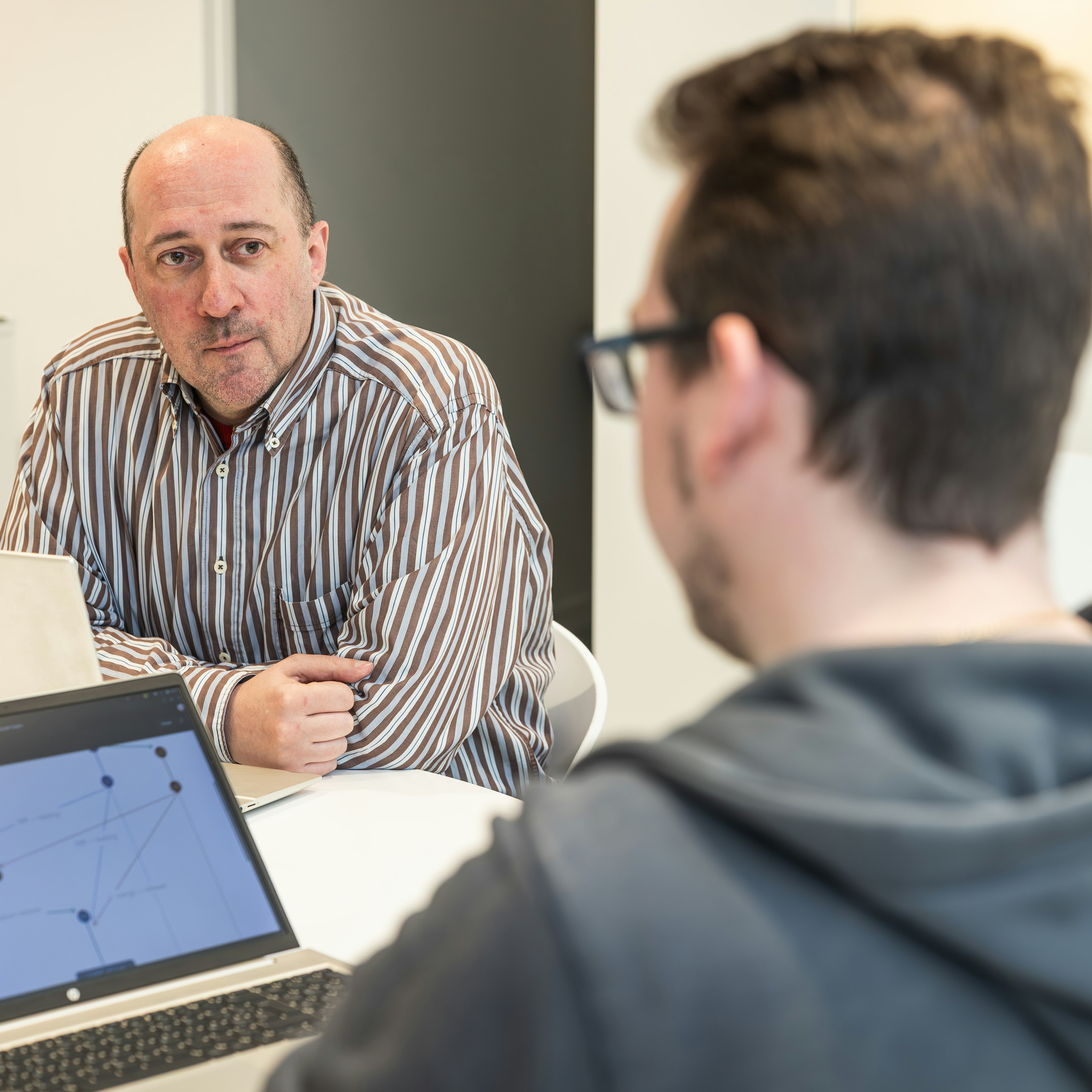 Two colleagues in discussion over a laptop diagram