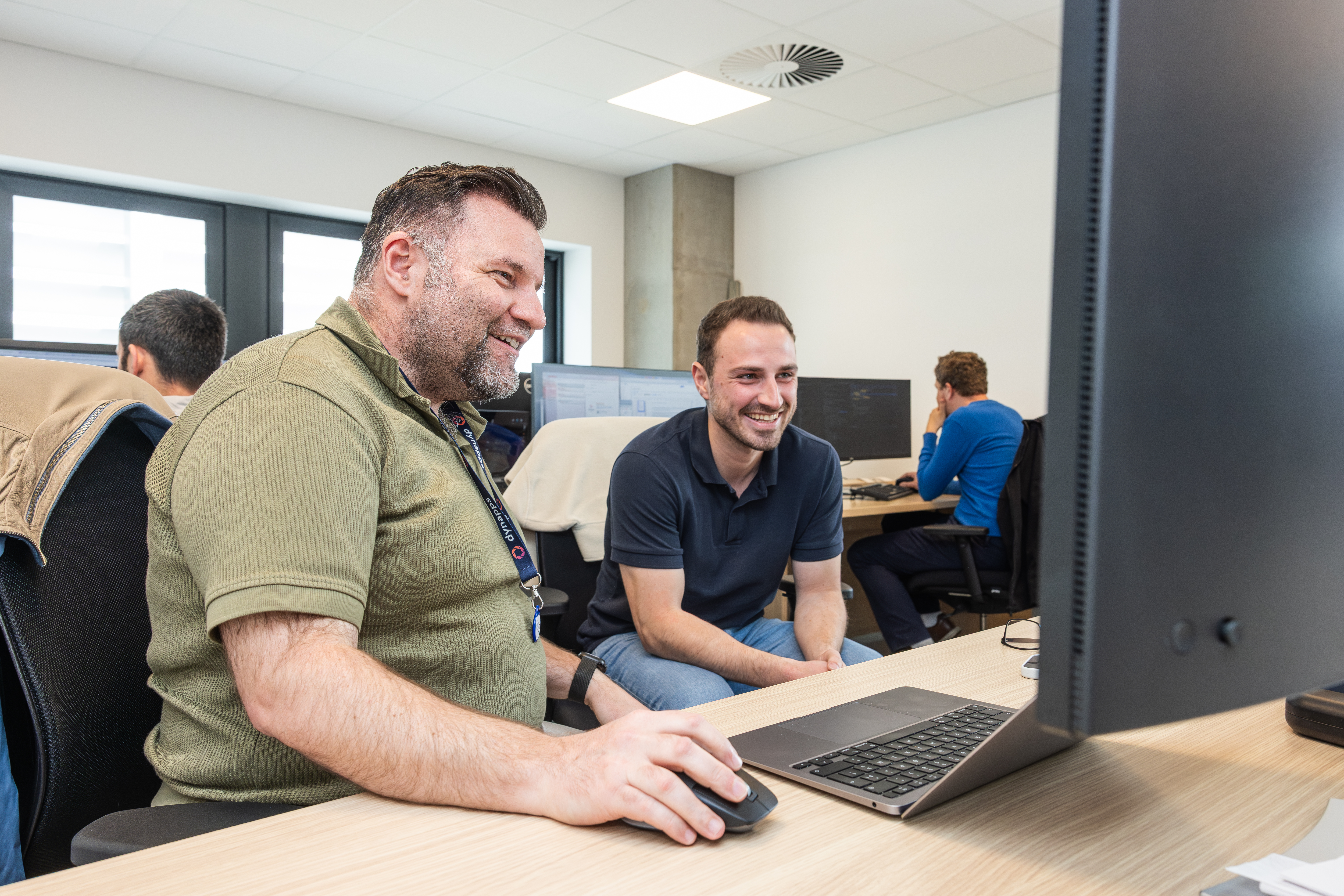 Deux collègues de Dynapps souriant devant l'écran d'un ordinateur portable