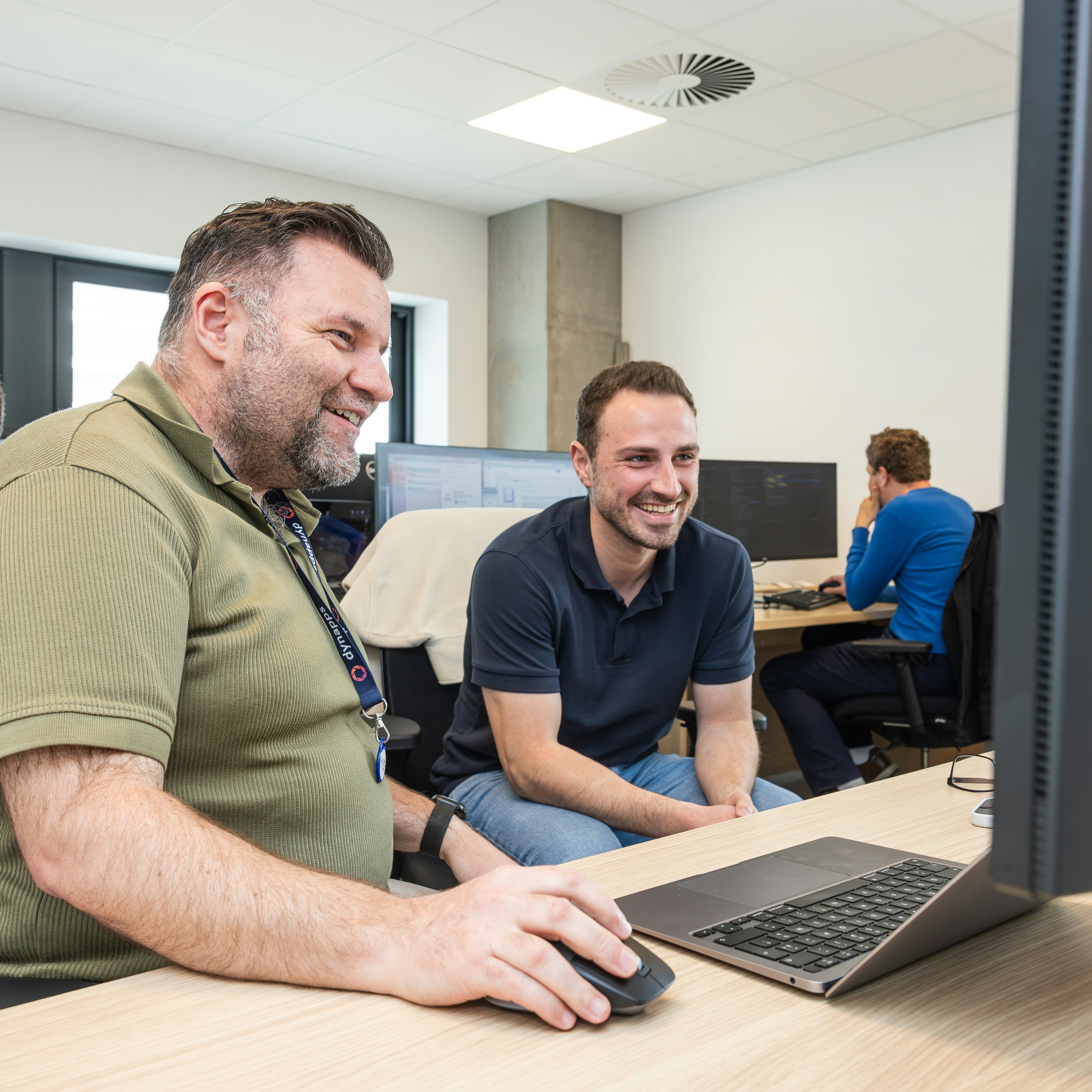 Deux collègues de Dynapps souriant devant l'écran d'un ordinateur portable