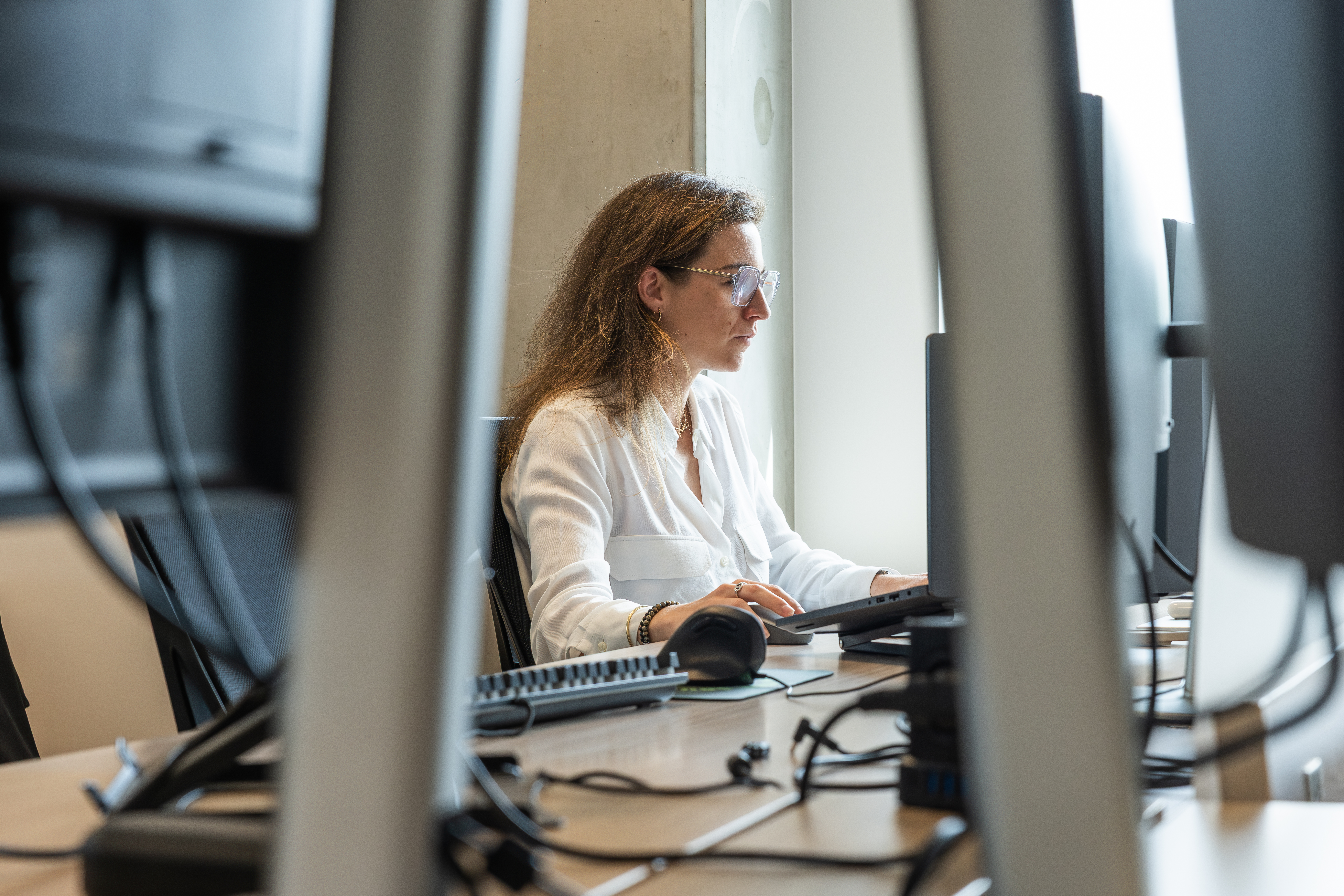 Woman in white blouse typing at her workstation