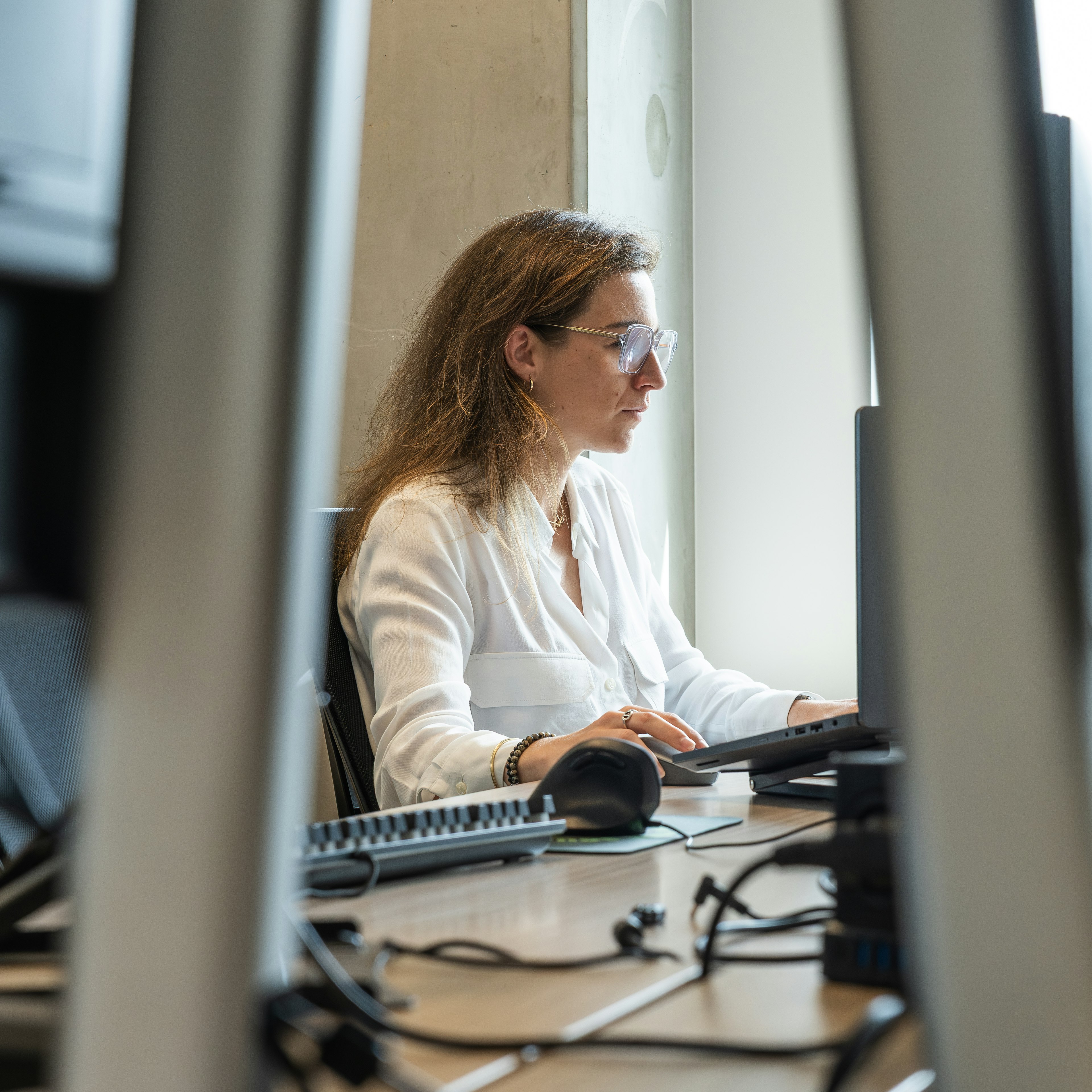 Woman in white blouse typing at her workstation