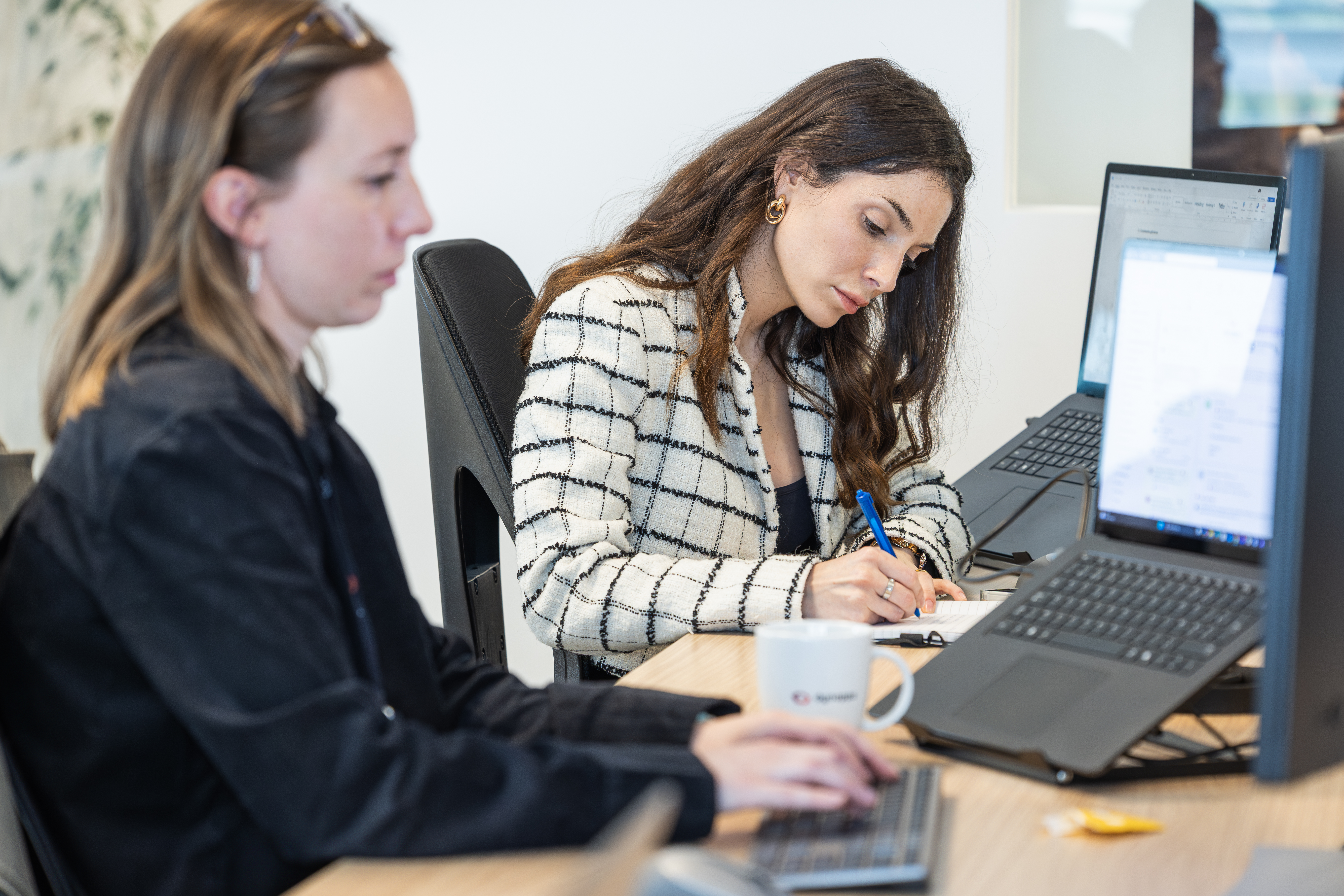 Deux consultants penchés sur leur travail à leur bureau, devant leur ordinateur portable