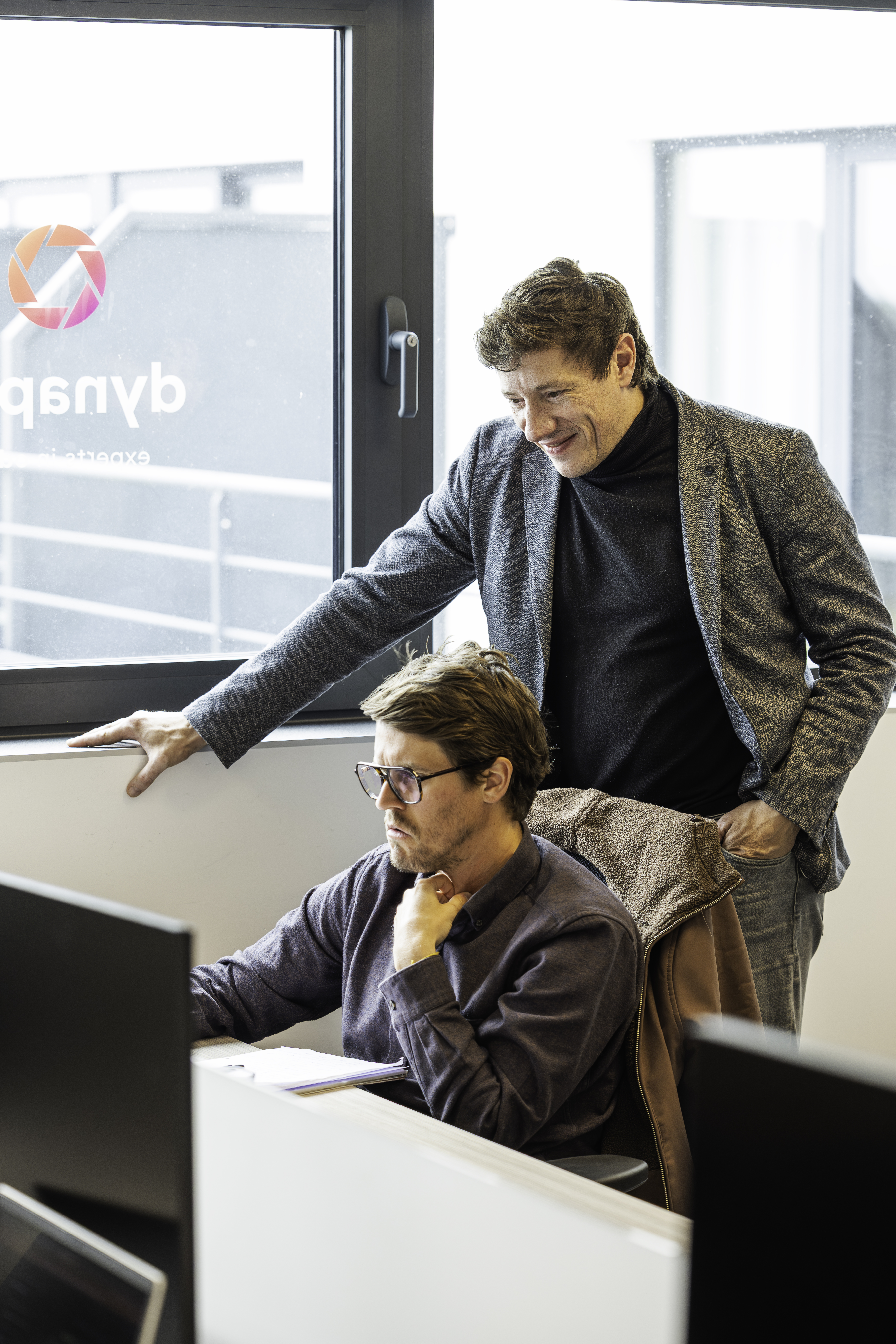 Deux collègues examinent un écran près du logo Dynapps