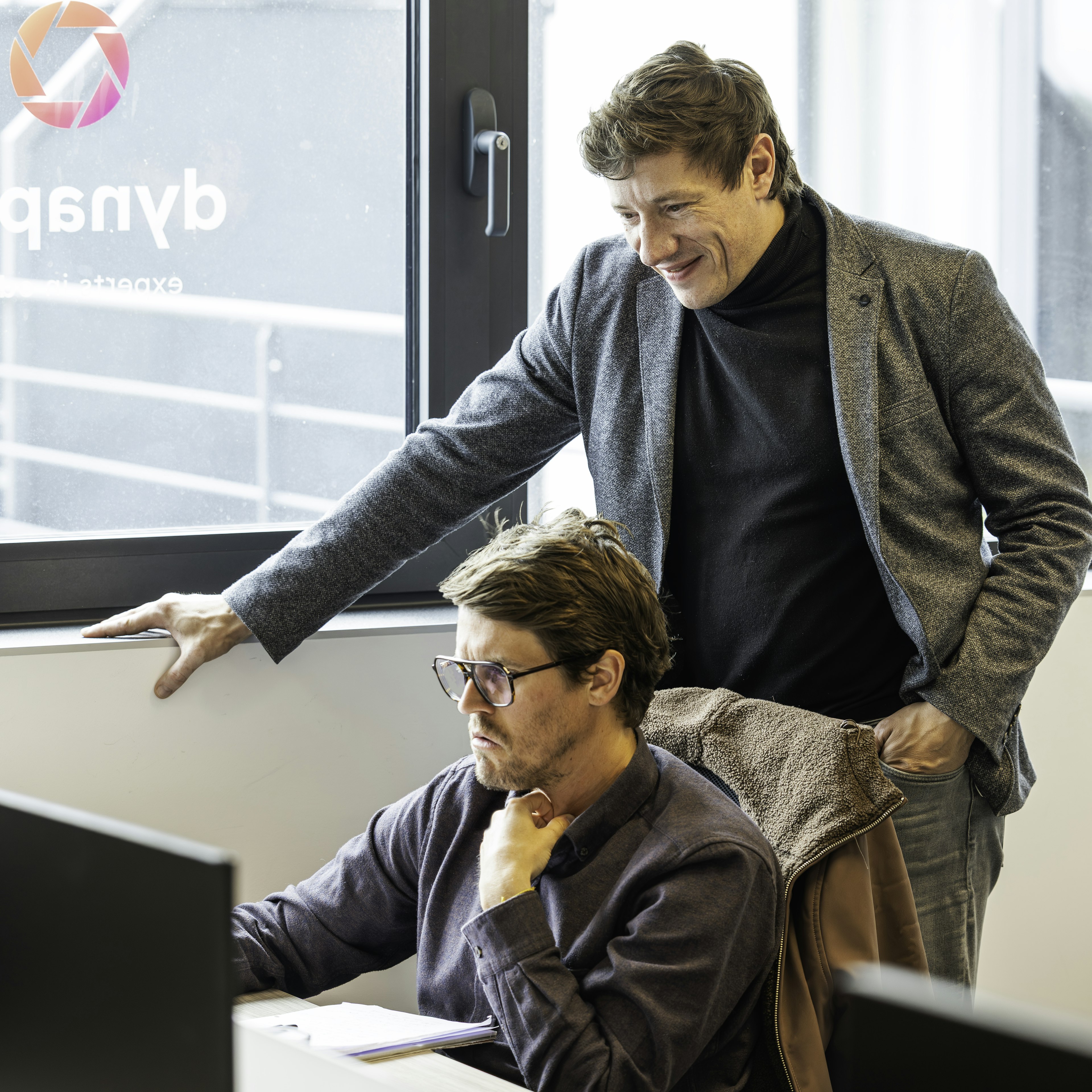 Deux collègues examinent un écran près du logo Dynapps