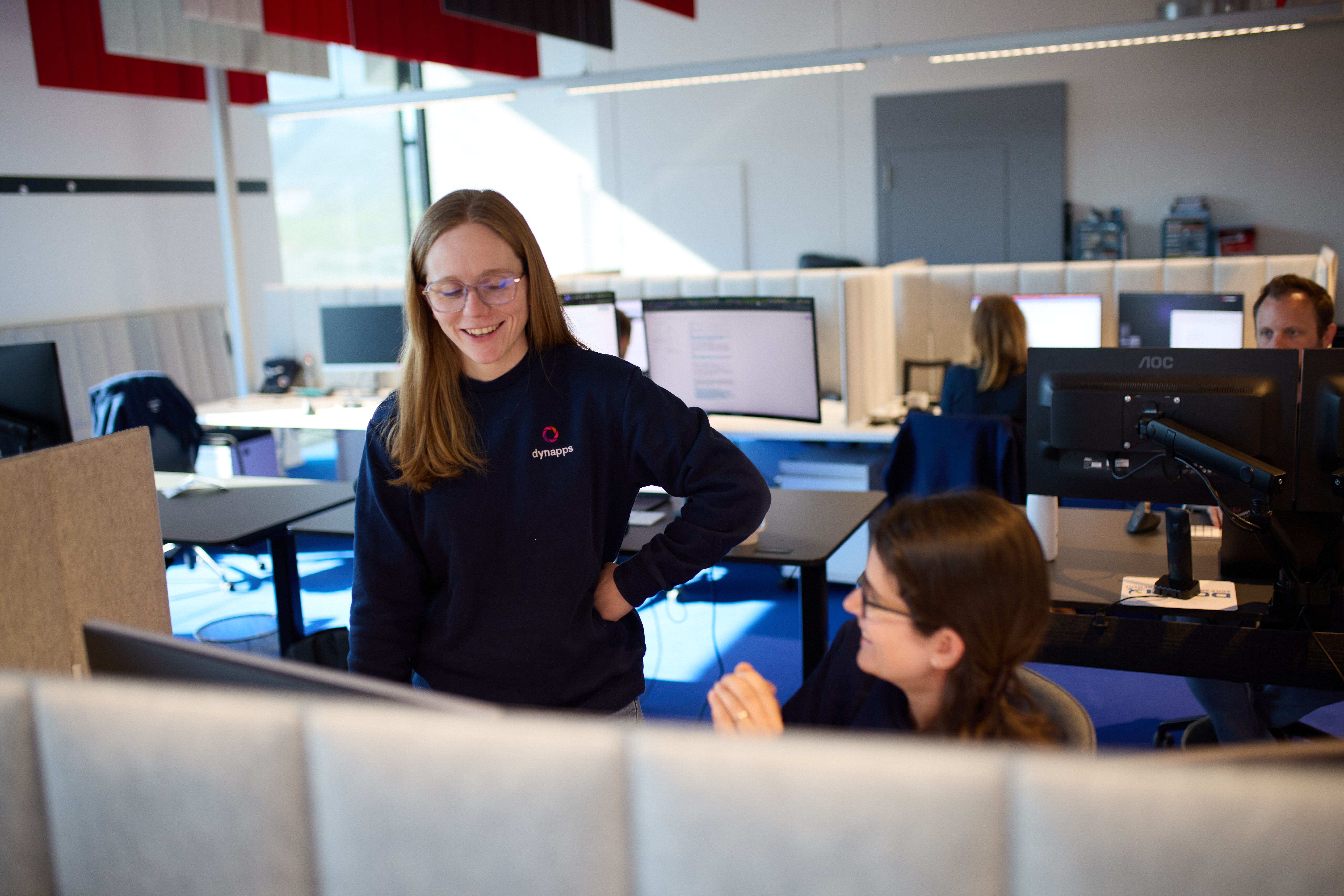 Two female colleagues talking at a desk