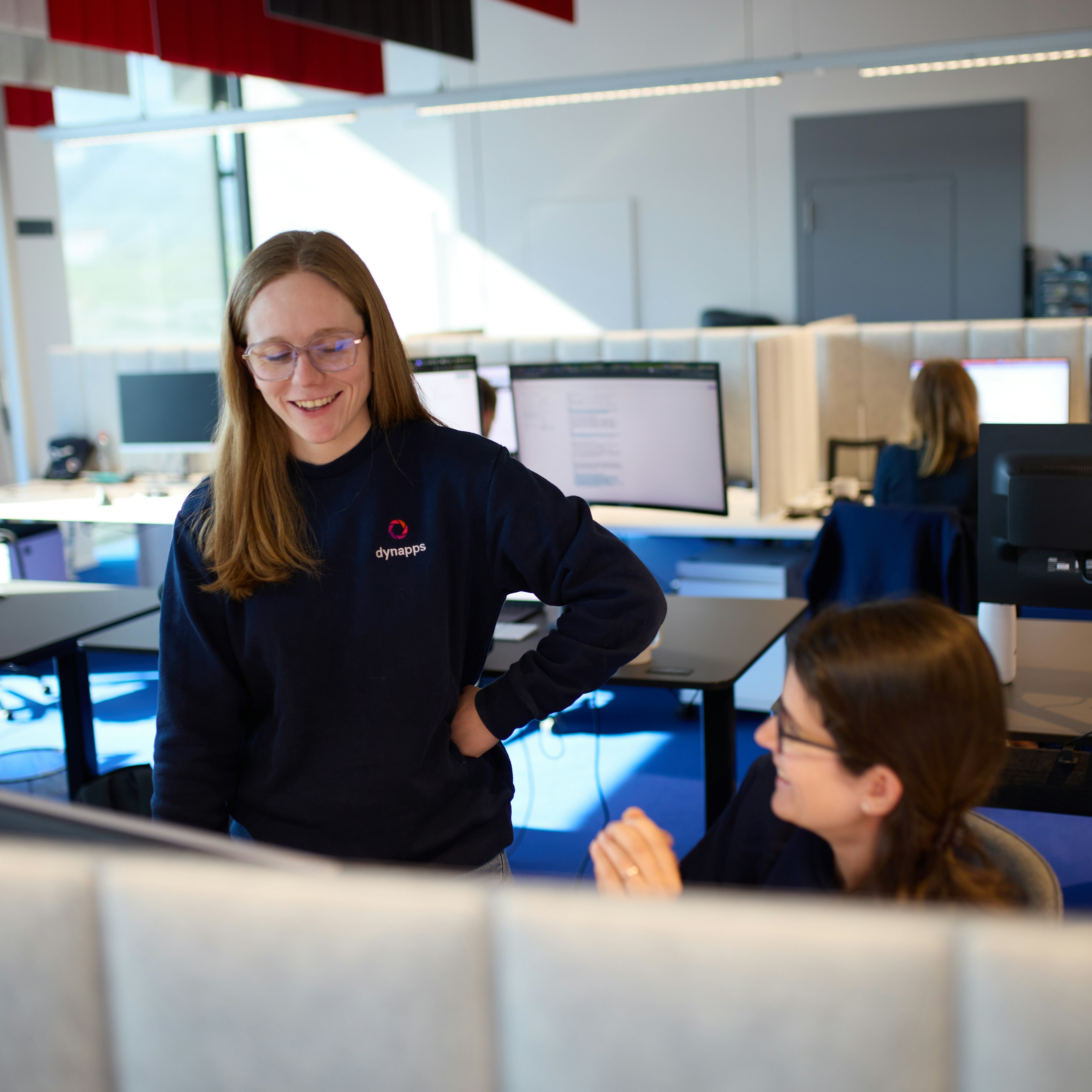 Two female colleagues talking at a desk