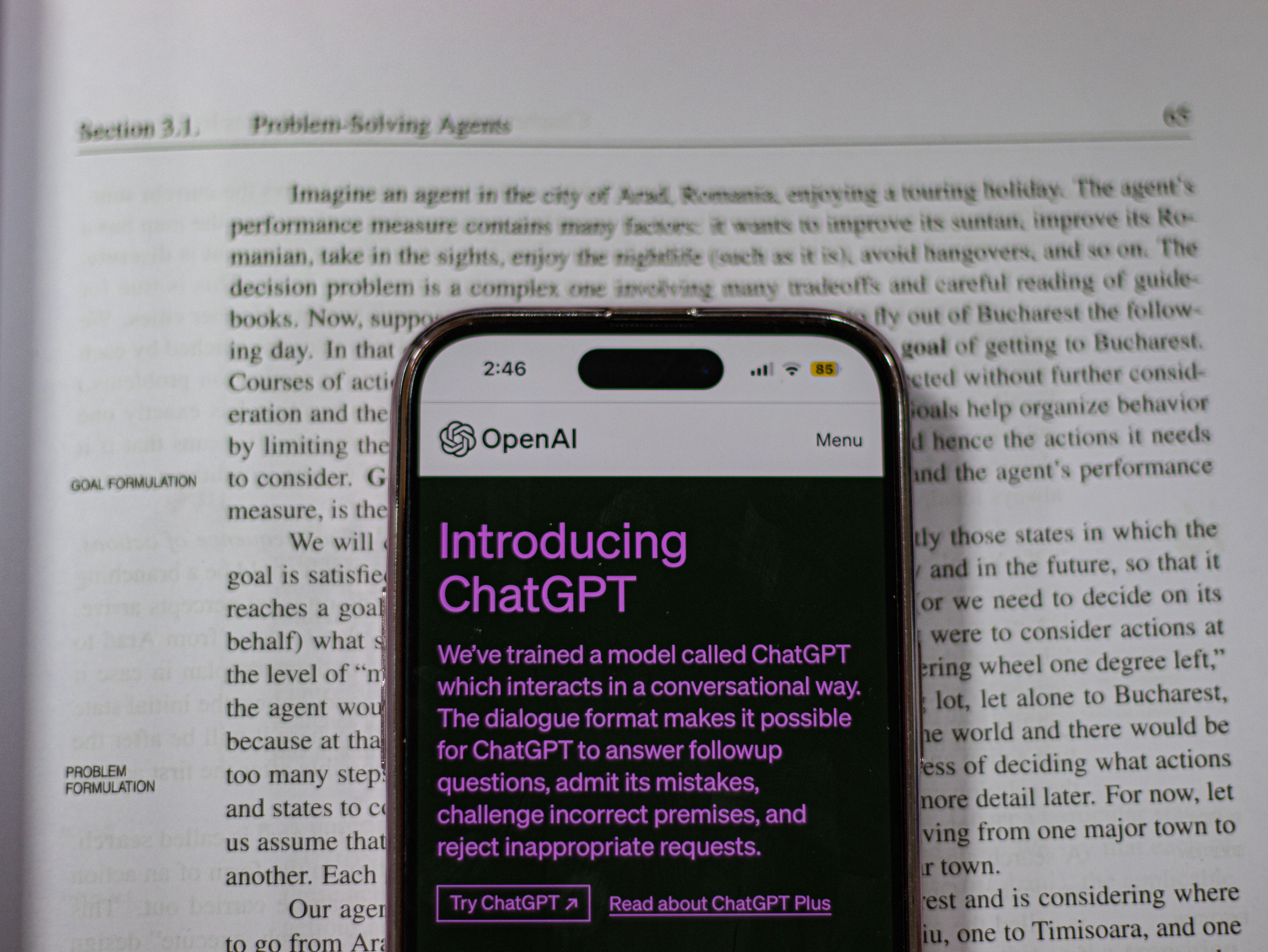 This image shows a smartphone displaying the OpenAI webpage titled "Introducing ChatGPT," superimposed over an open textbook page discussing "Section 3.1. Problem-Solving Agents" in artificial intelligence.