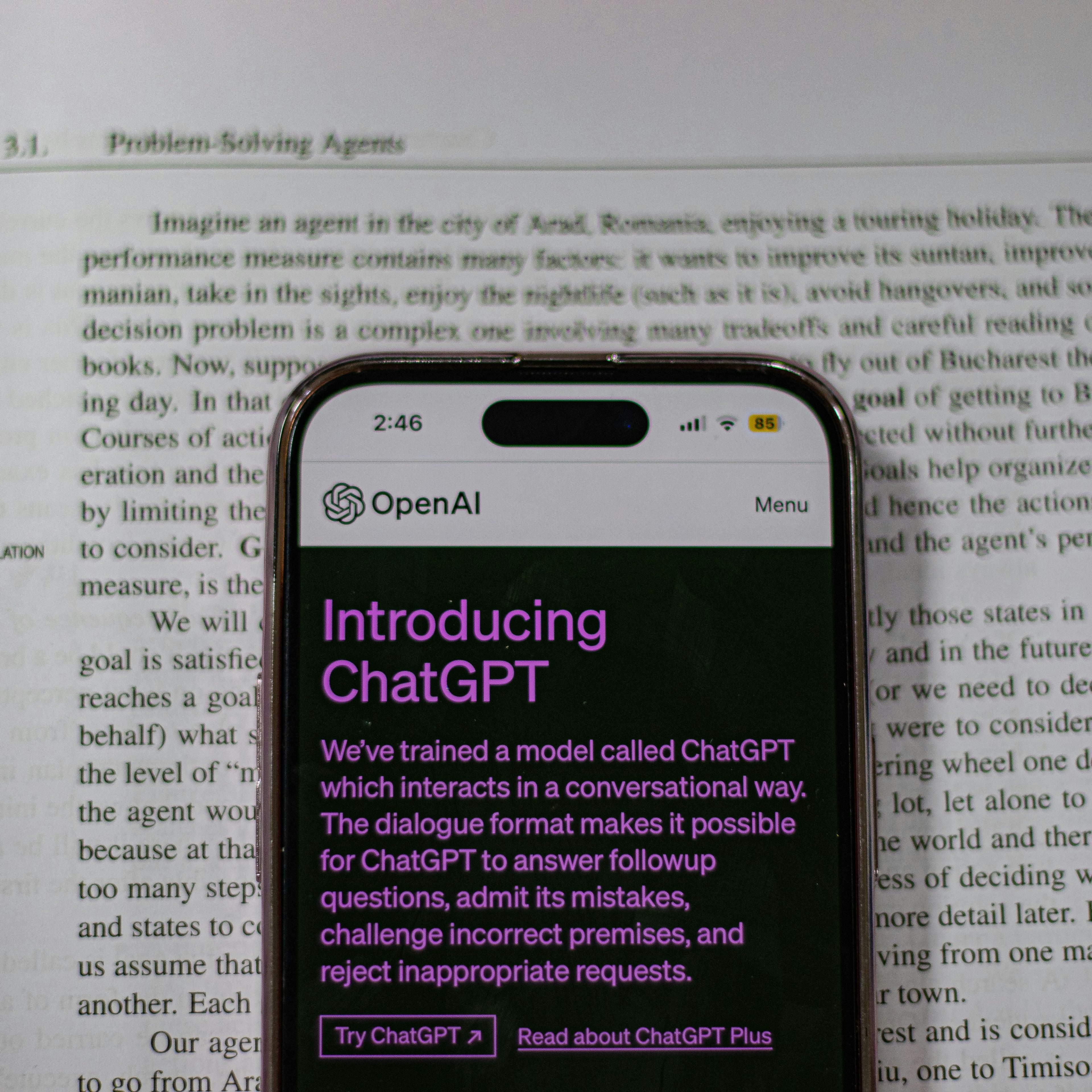 This image shows a smartphone displaying the OpenAI webpage titled "Introducing ChatGPT," superimposed over an open textbook page discussing "Section 3.1. Problem-Solving Agents" in artificial intelligence.