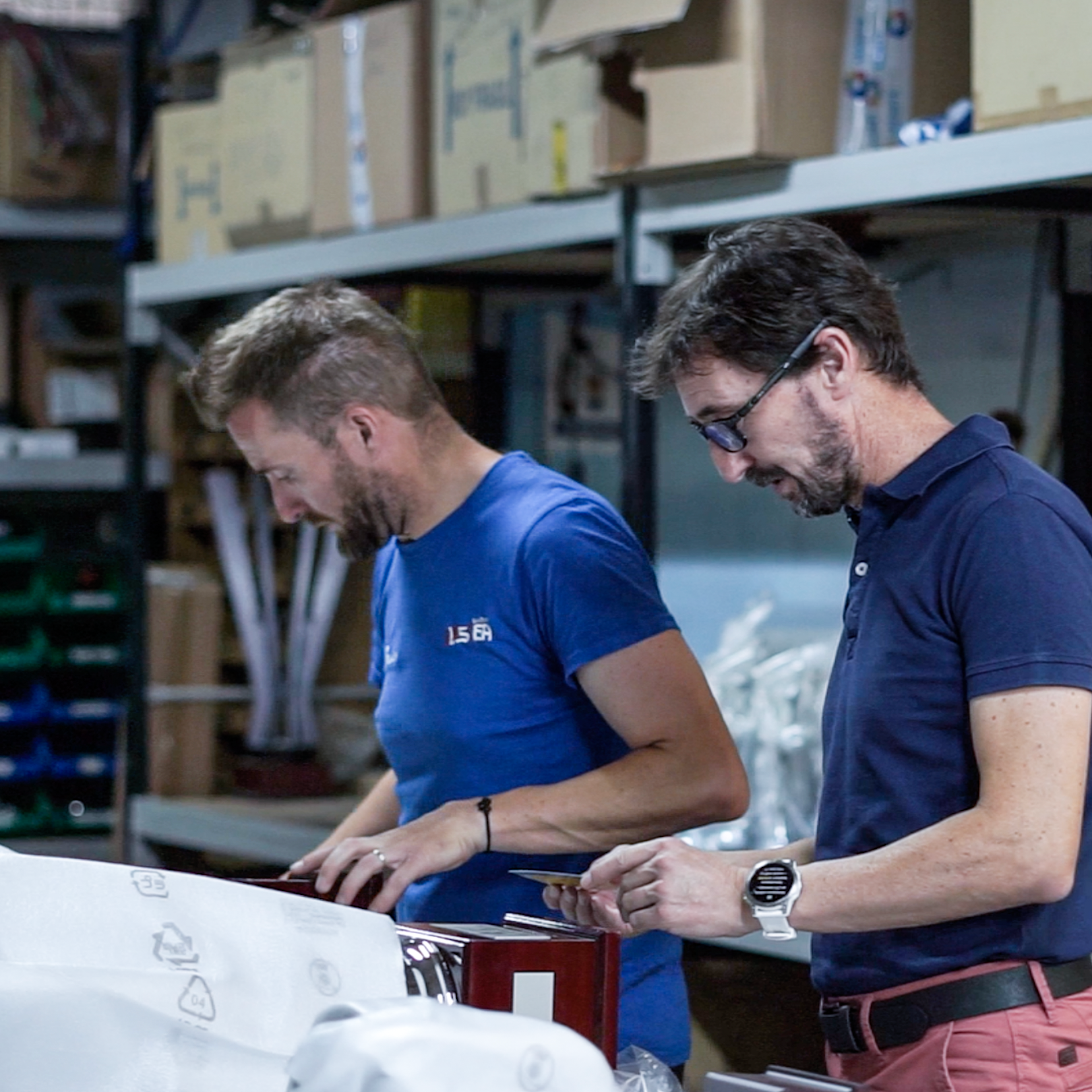 Two workers packing finished products at a bench in a warehouse