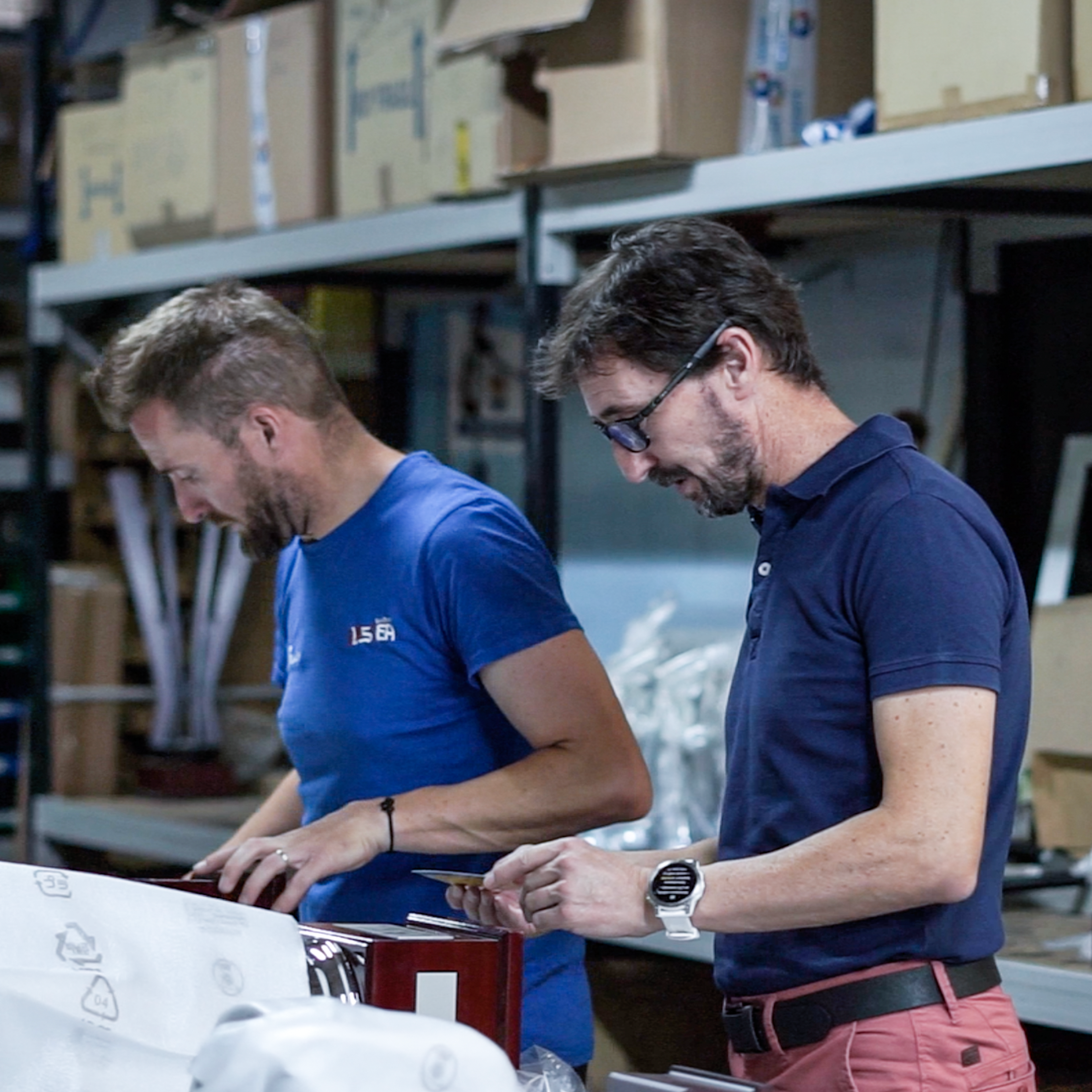 Twee medewerkers pakken afgewerkte producten in aan een werkbank in een magazijn