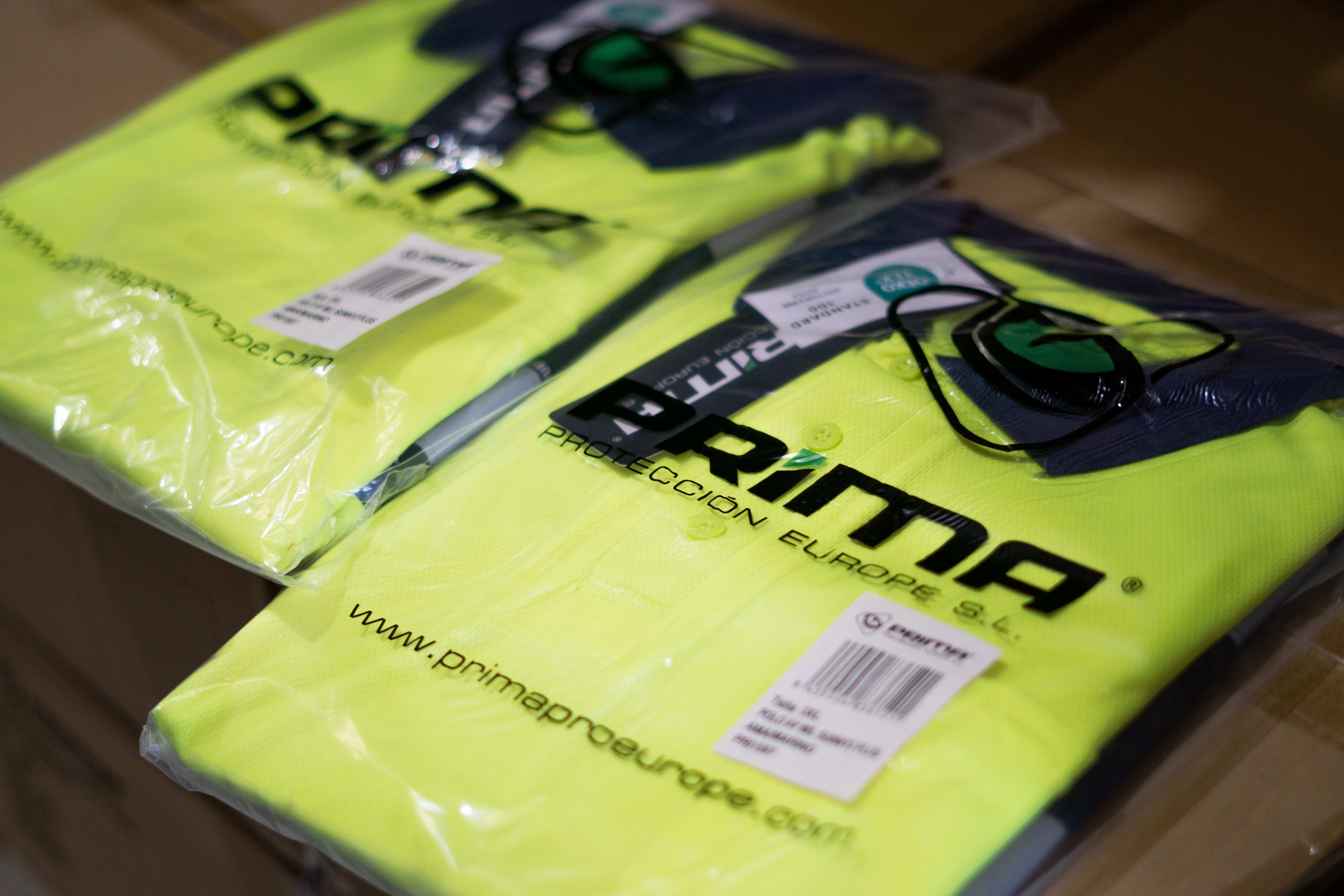 Close-up of folded high-visibility workwear in branded Prima Protección Europe packaging.