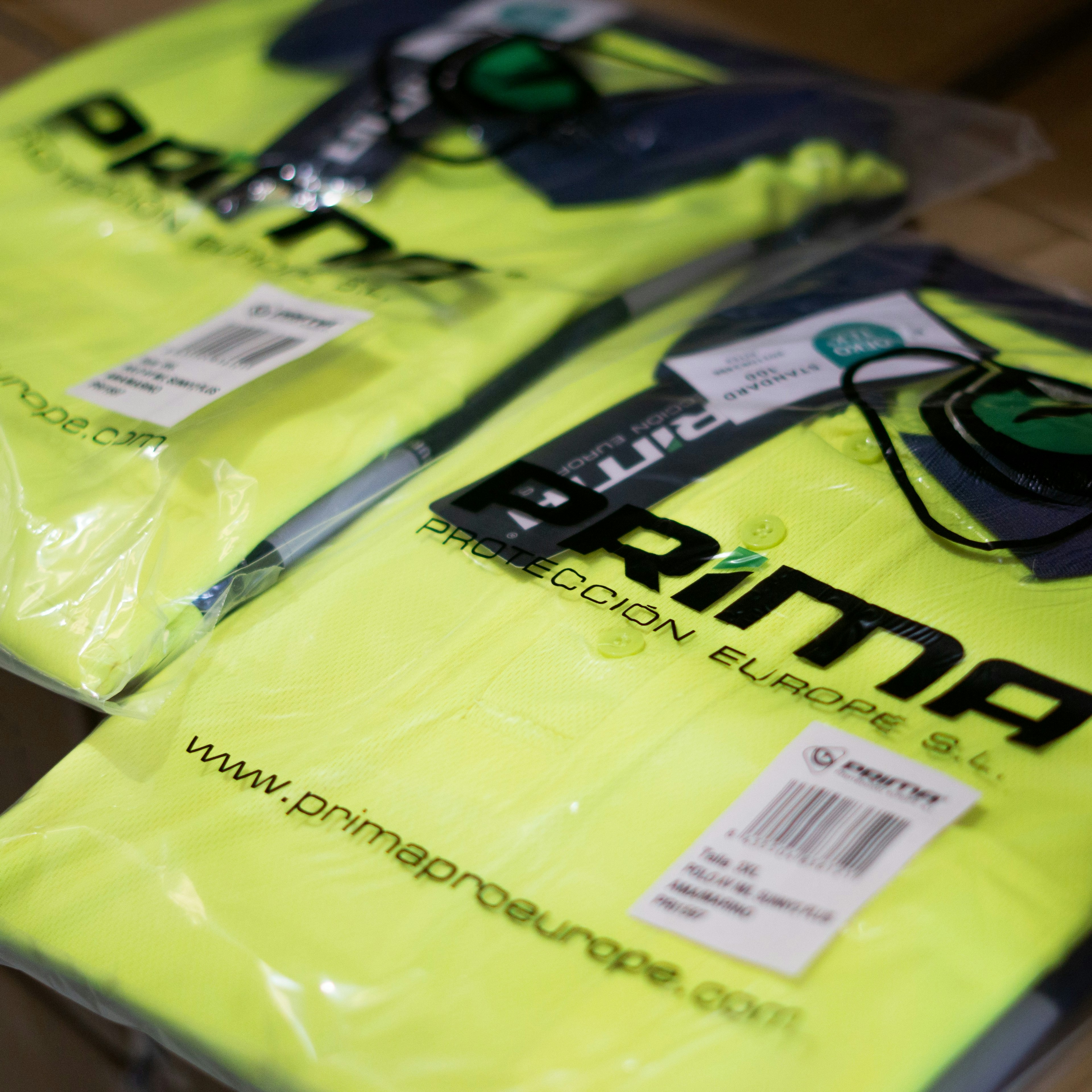 Close-up of folded high-visibility workwear in branded Prima Protección Europe packaging.