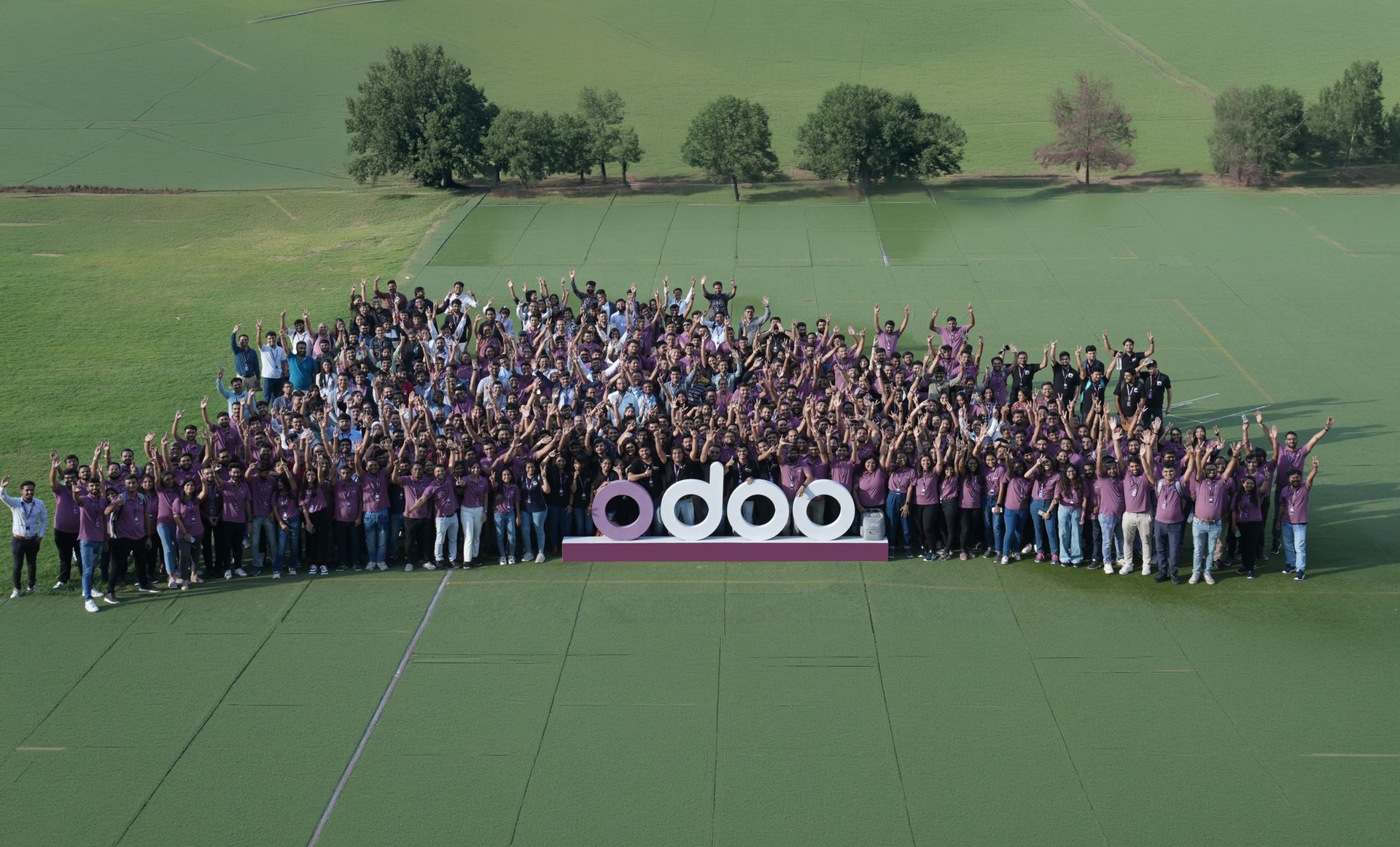 a group of more than 100 people surrounding the Odoo logo