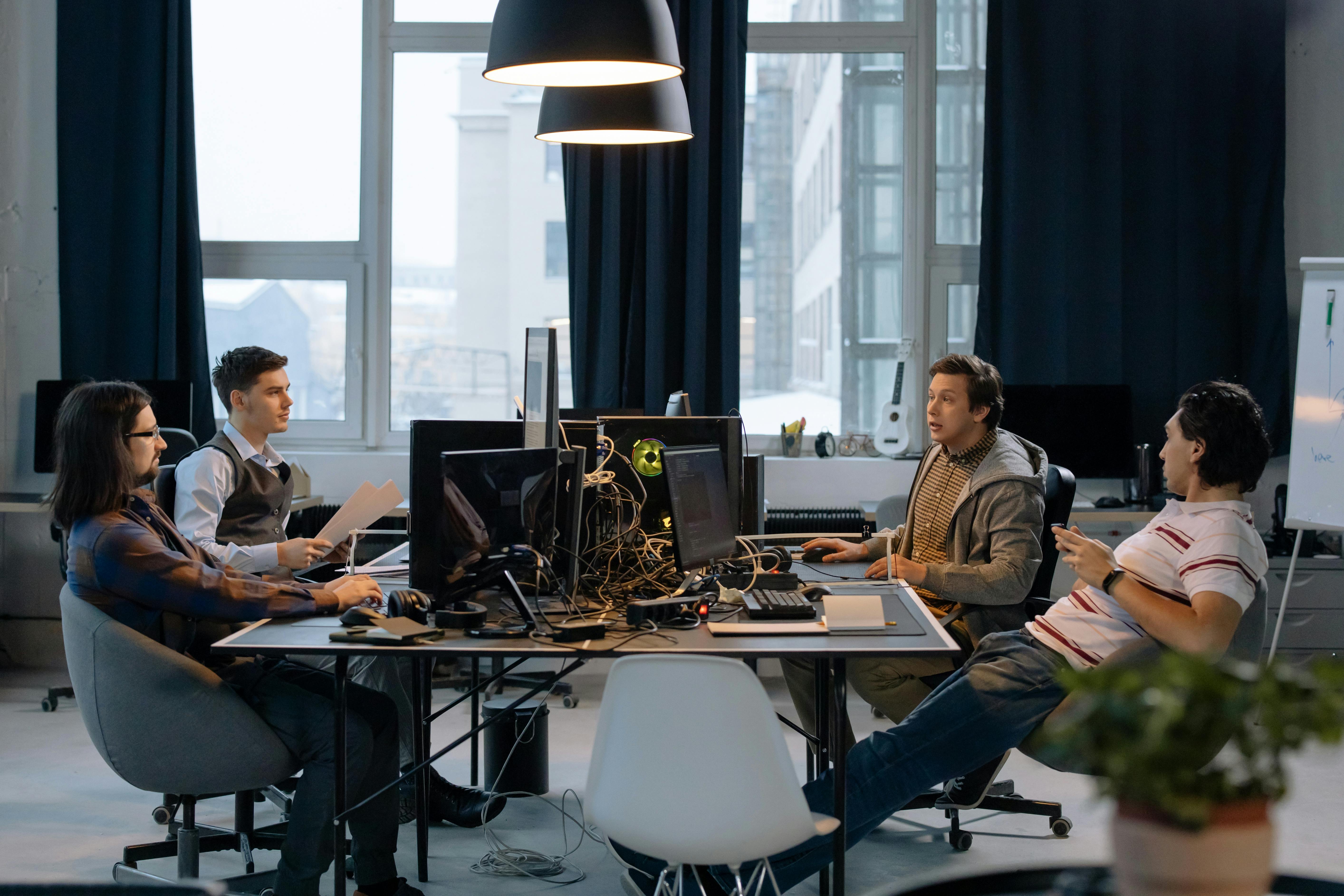 A modern office space featuring meeting rooms, black furniture, and contemporary furnishings designed to foster business collaboration.