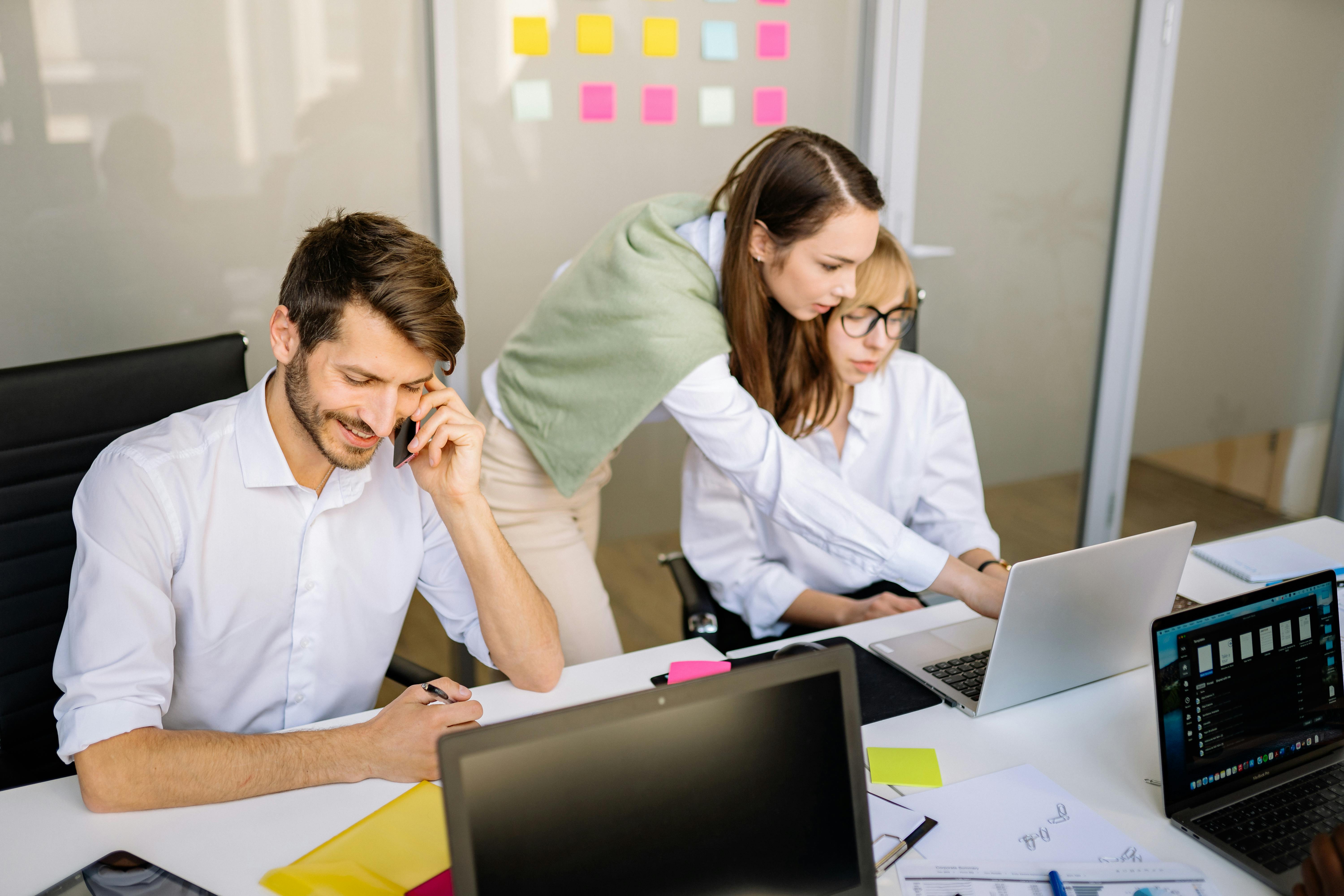 A team working on a project with sticky notes on the wall and a laptop on the desk.