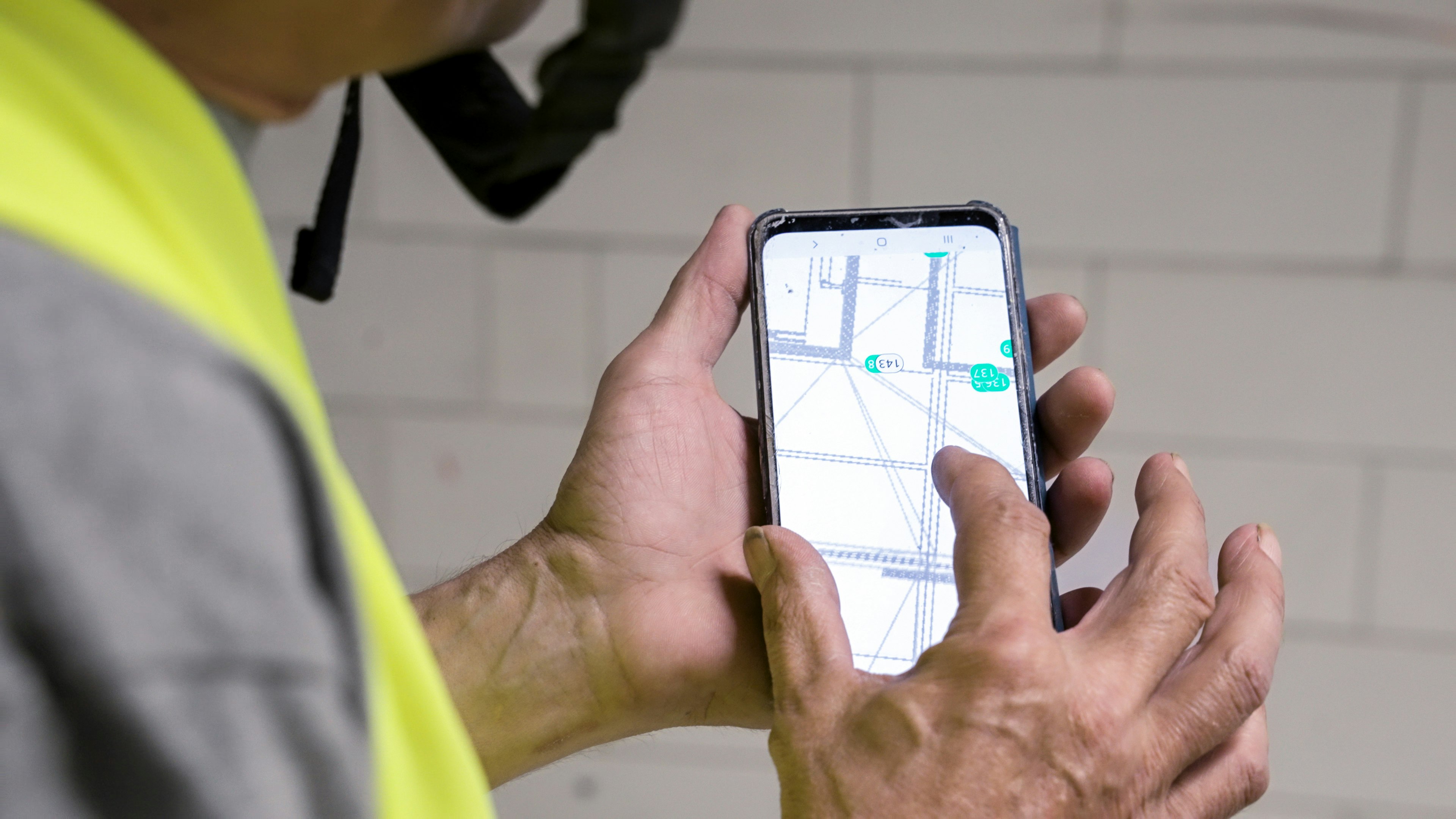 Technician checking an annotated floor plan on a phone on site