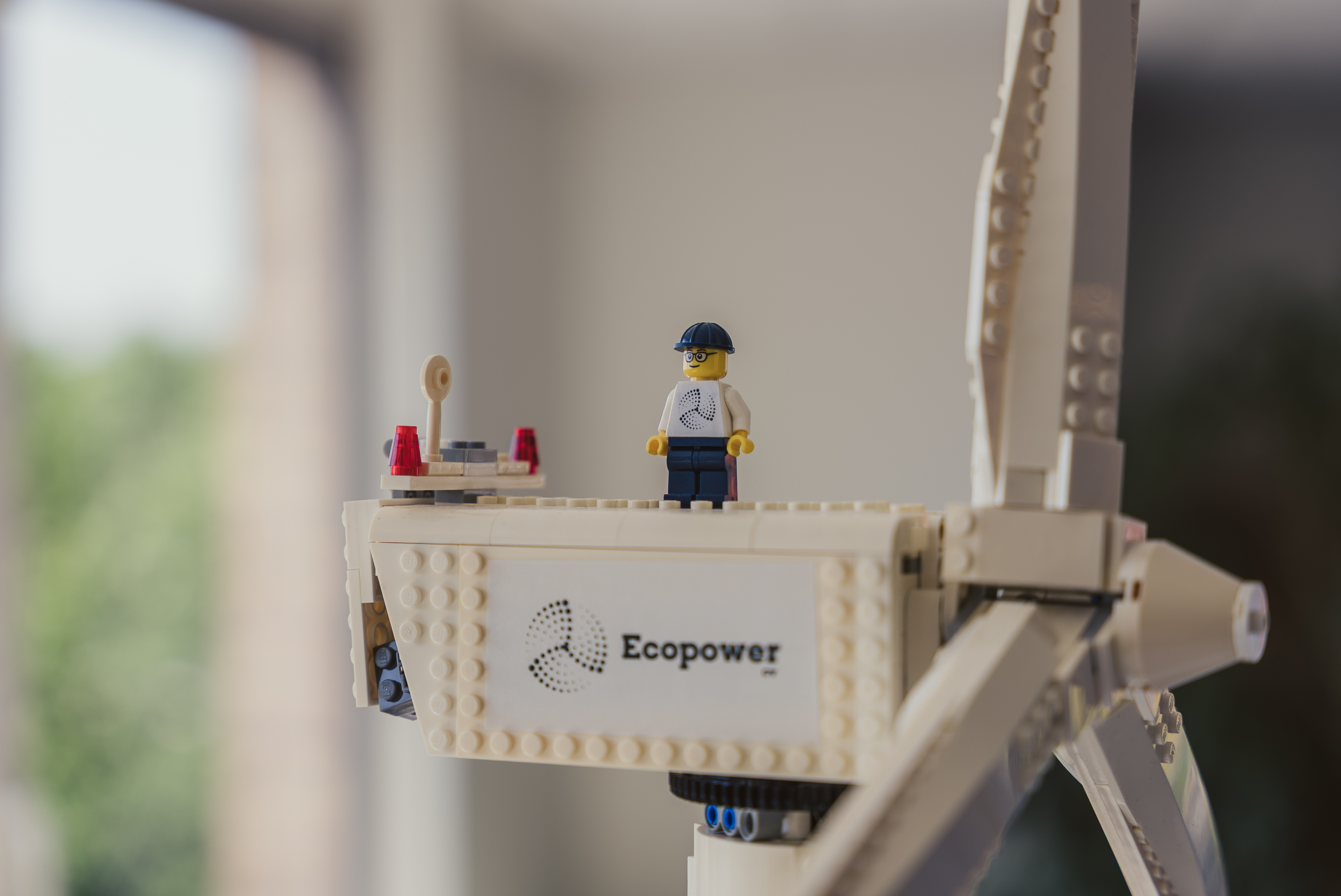 Close-up of a model wind turbine carrying the Ecopower logo, with a small figurine standing on the nacelle.
