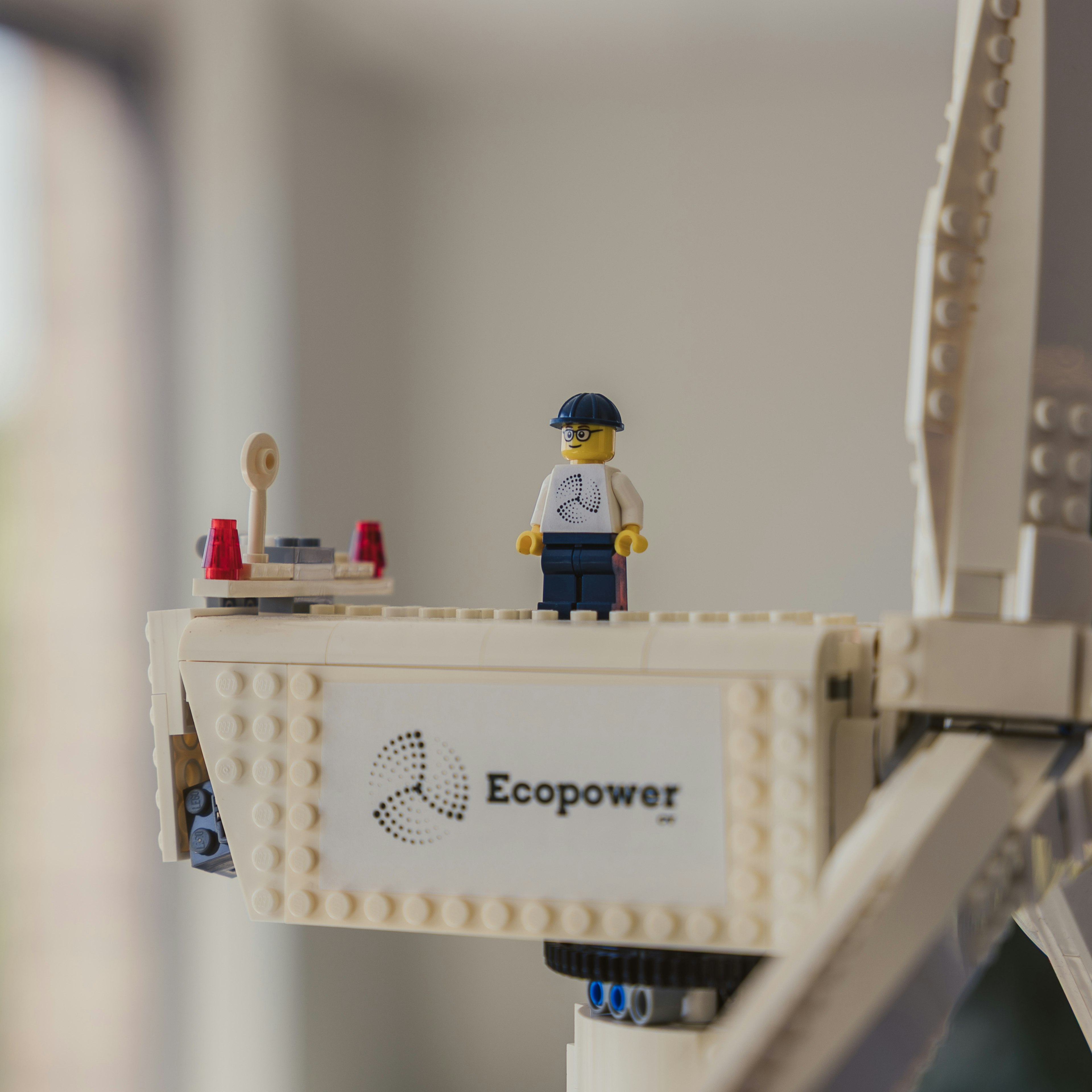 Close-up of a model wind turbine carrying the Ecopower logo, with a small figurine standing on the nacelle.