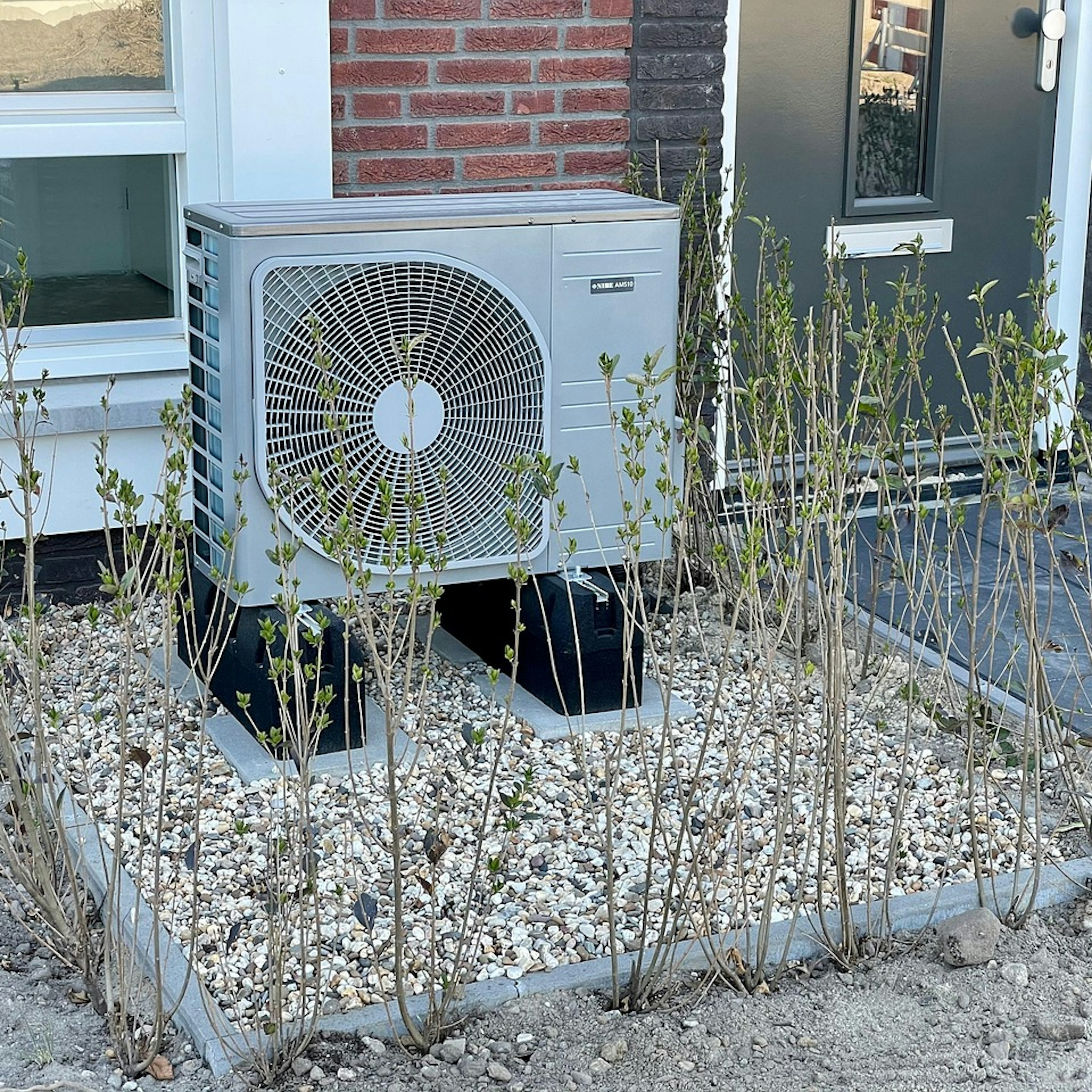 Outdoor heat pump unit installed in front of a house