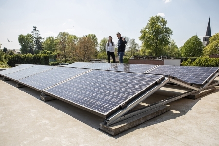 Deux personnes à côté de panneaux solaires sur un toit plat
