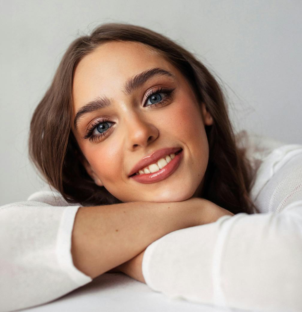 woman smiling while leaning head in arms