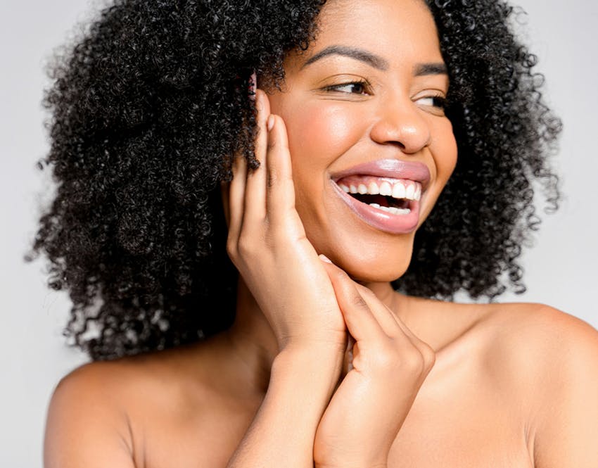 woman smiling holding head in hands