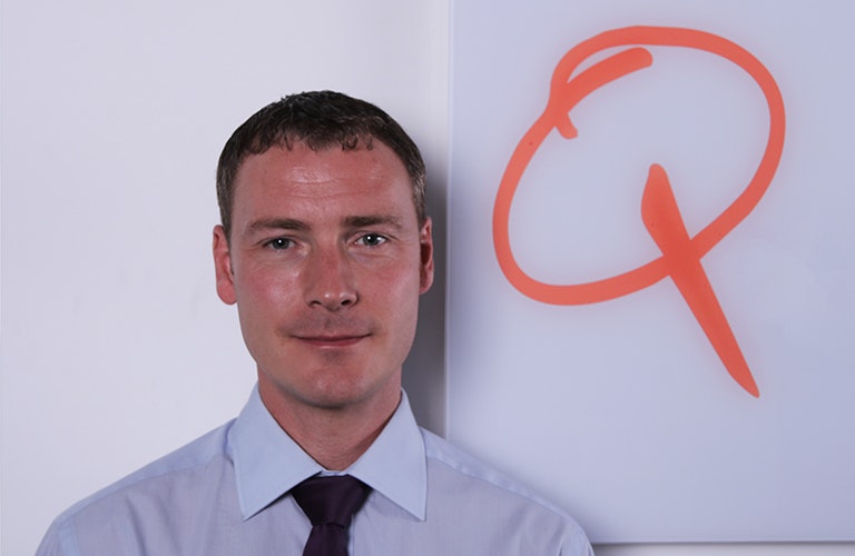 Phil Nicholson standing next to the Q Catering Logo 