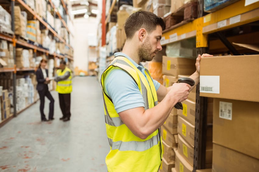 A man in a high vis searching the GTINs of products in a large warehouse