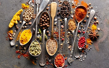 a colourful array of herbs and spices on various gold and silver brass spoons