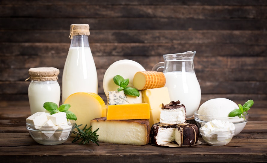 bottles of milk, cheese and cream on a wooden table 