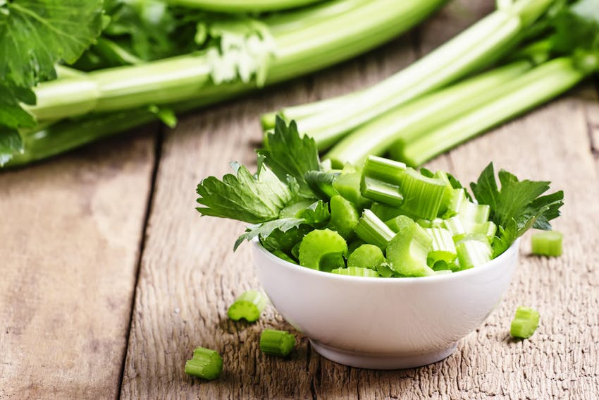 chopped celery in a small white bowl and celery sticks 