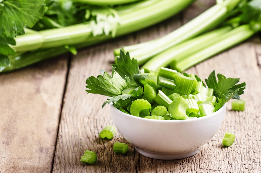 chopped celery in a small white bowl and celery sticks 