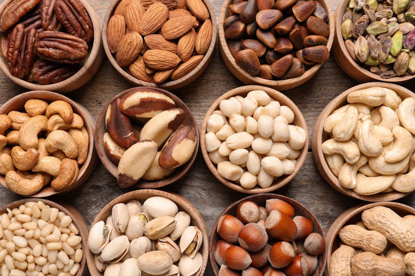 various wooden bowls filled with different types of tree nuts 