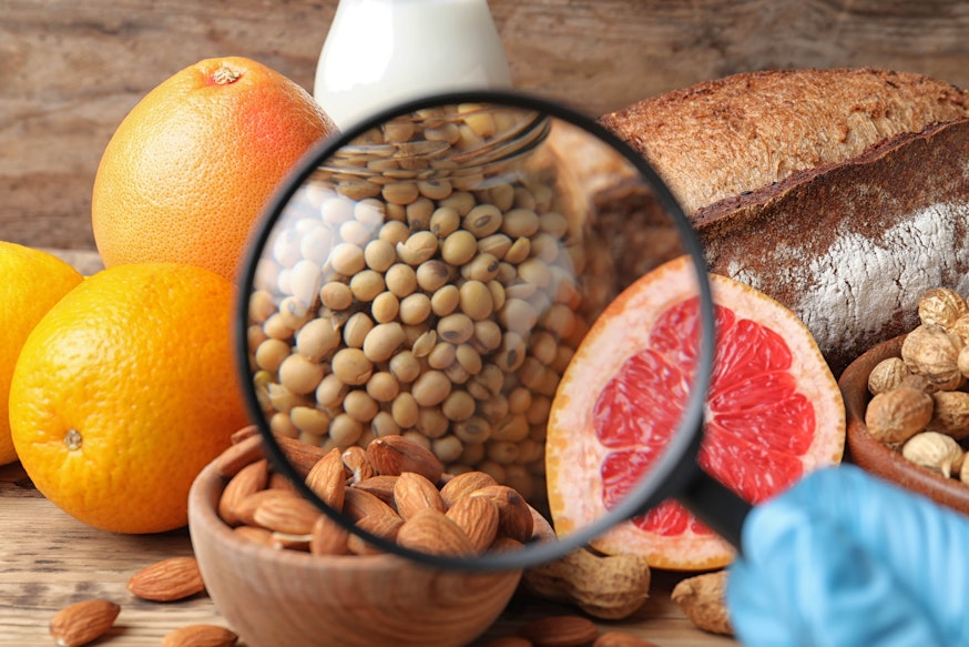 Hidden Allergens a magnifying glass focusing in on almonds, crustaceans, soyabeans, eggs and grapefruit