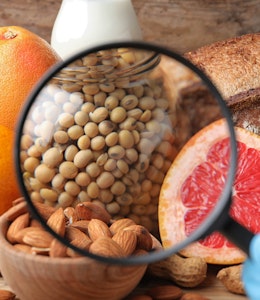 a magnifying glass focusing in on almonds, crustaceans, soyabeans, eggs and grapefruit