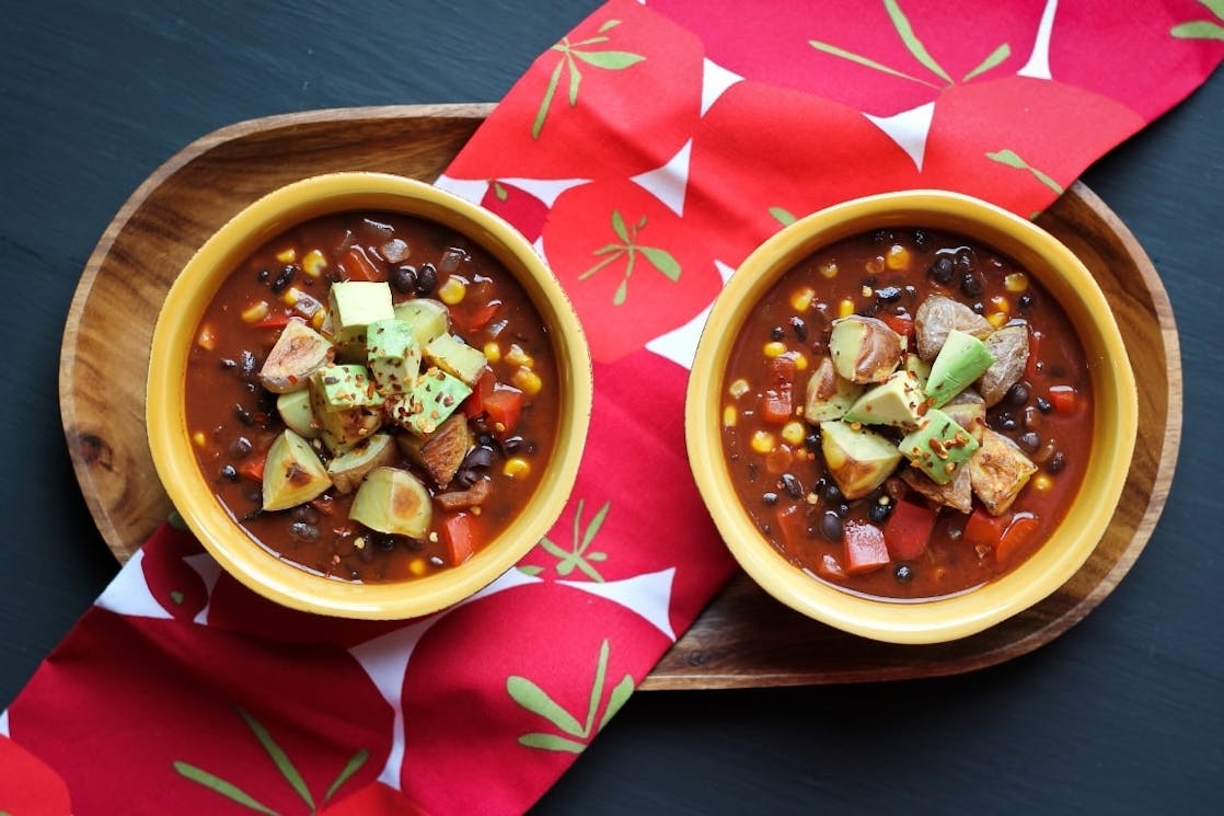Vegan Chilli with Cocoa two bowls of vegan chilli with cocoa served on a wooden tray