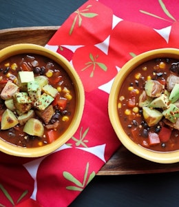 two bowls of vegan chilli with cocoa served on a wooden tray 