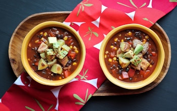 two bowls of vegan chilli with cocoa served on a wooden tray 