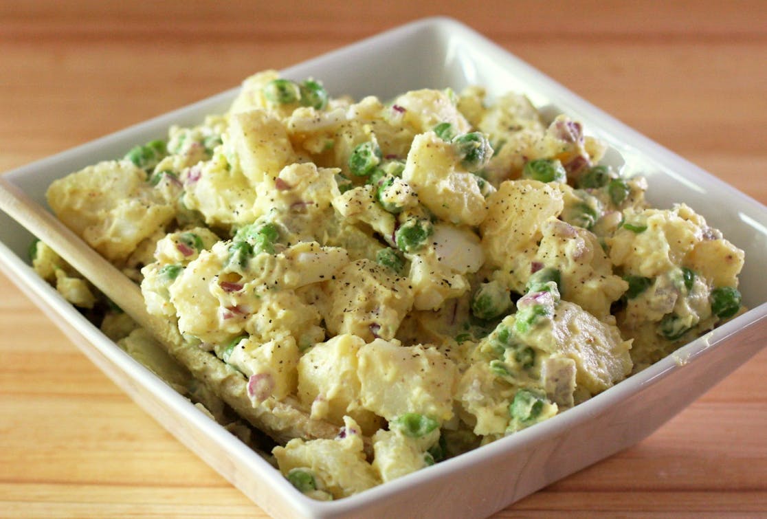 Potato, Bacon & Pea Salad square white dish filled with a creamy potato, bacon and pea salad